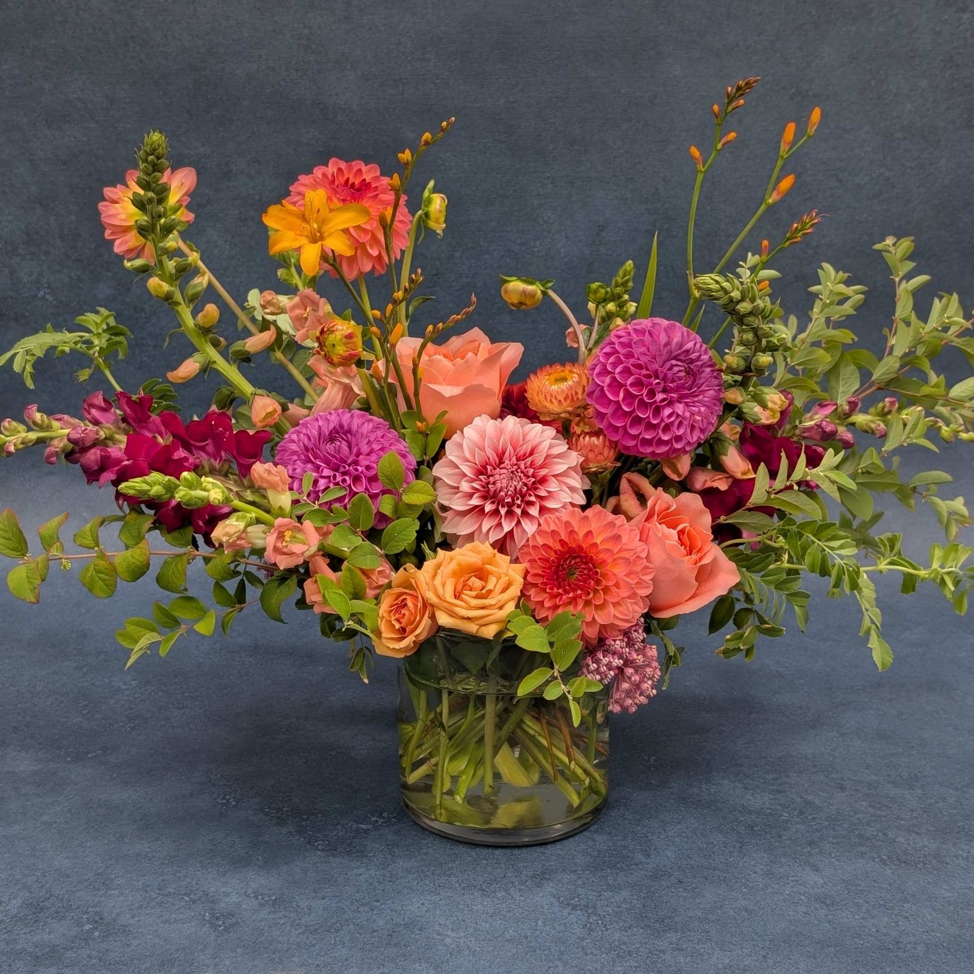 Mixed bouquet of pink, orange, and purple flowers in a glass vase
