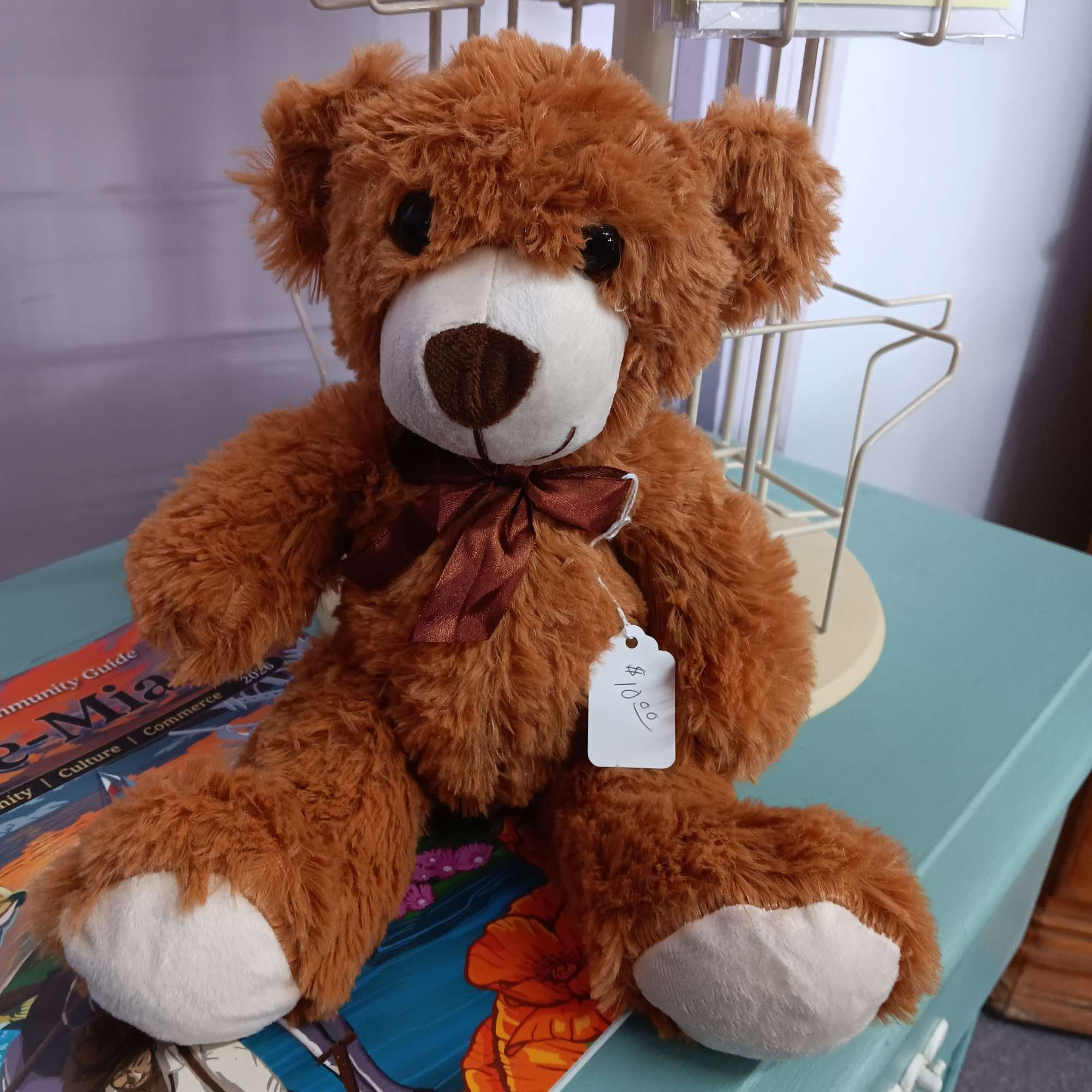 Brown teddy bear with a ribbon bow and price tag