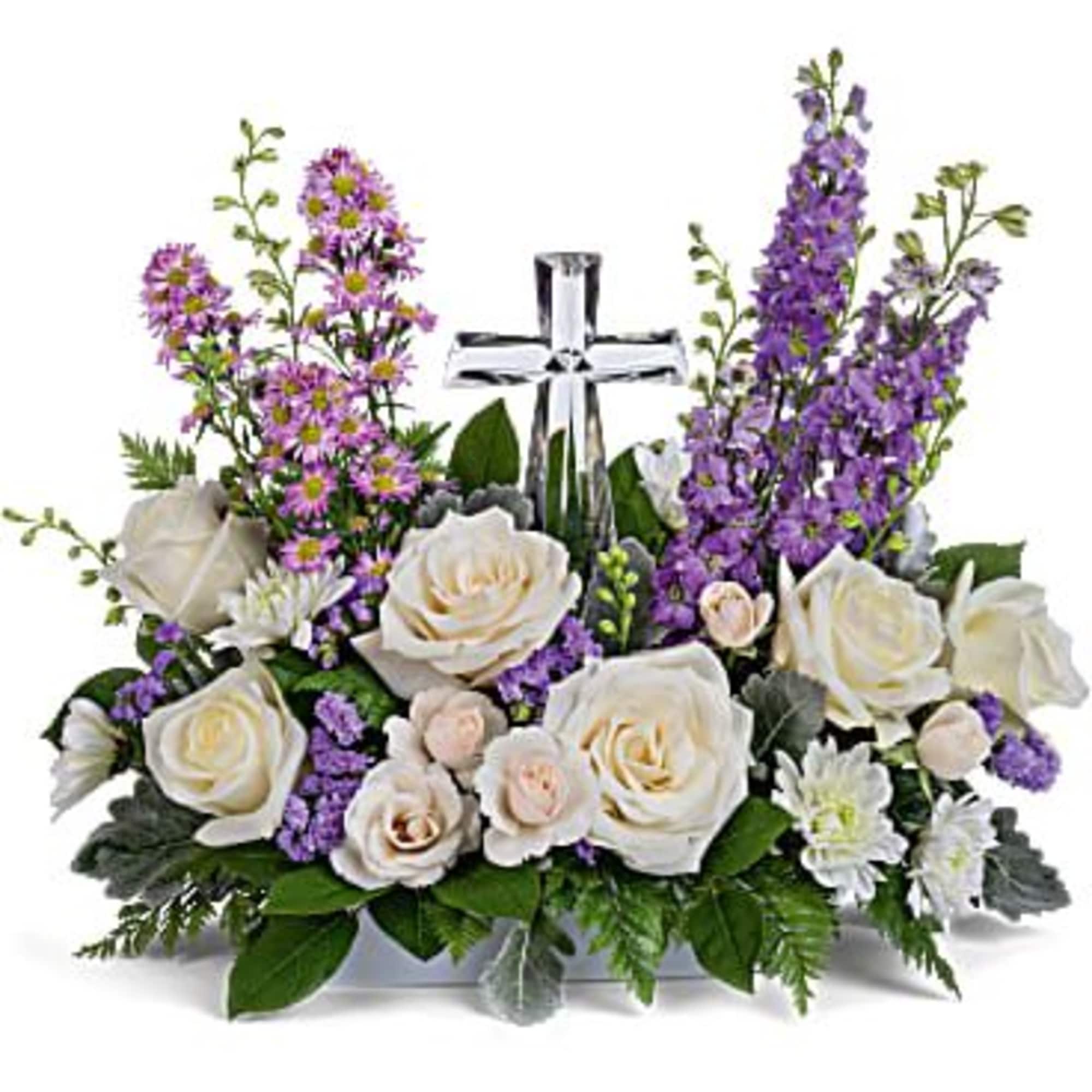 White roses and purple flowers arranged around a silver cross