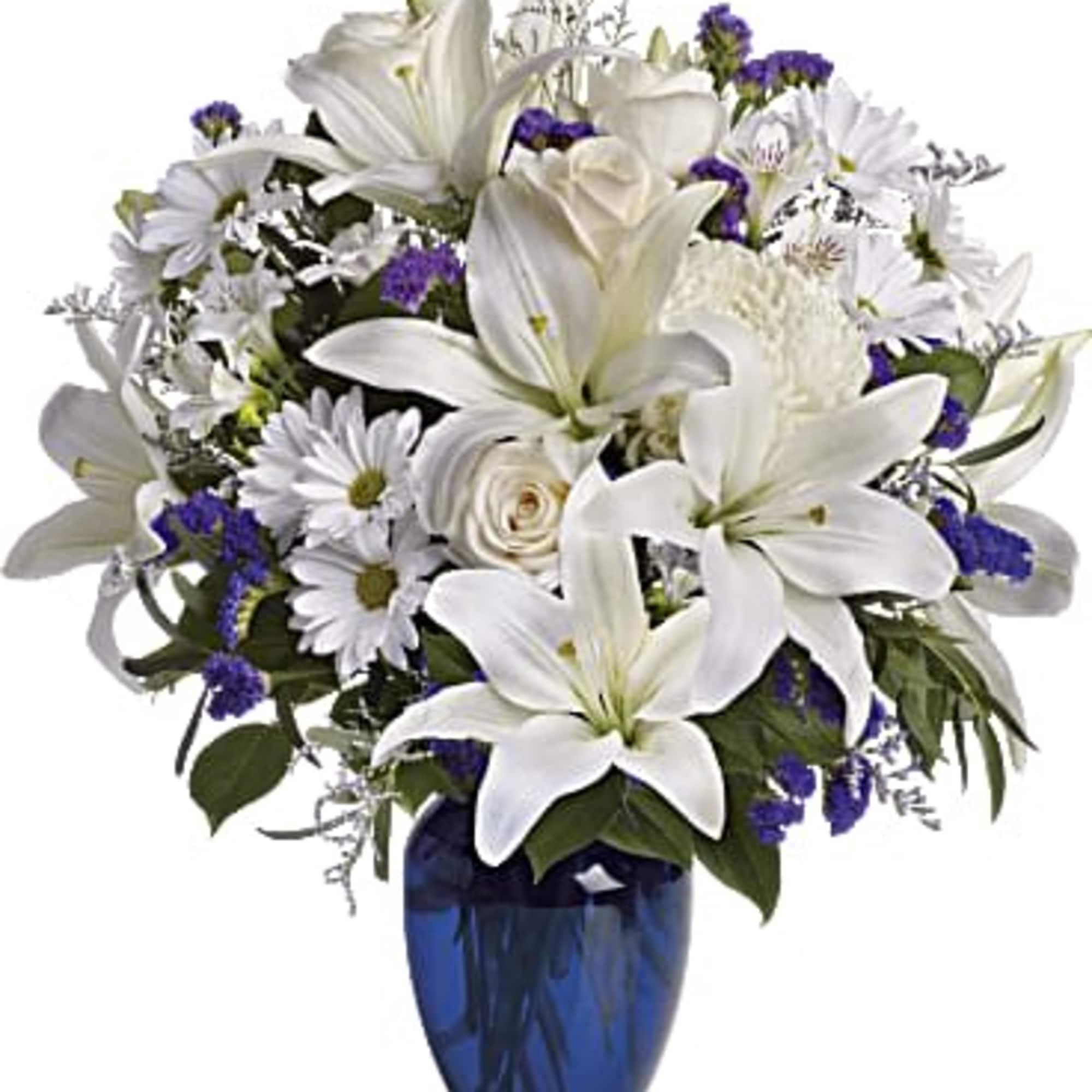 White lilies and daisies with purple accents in a blue vase