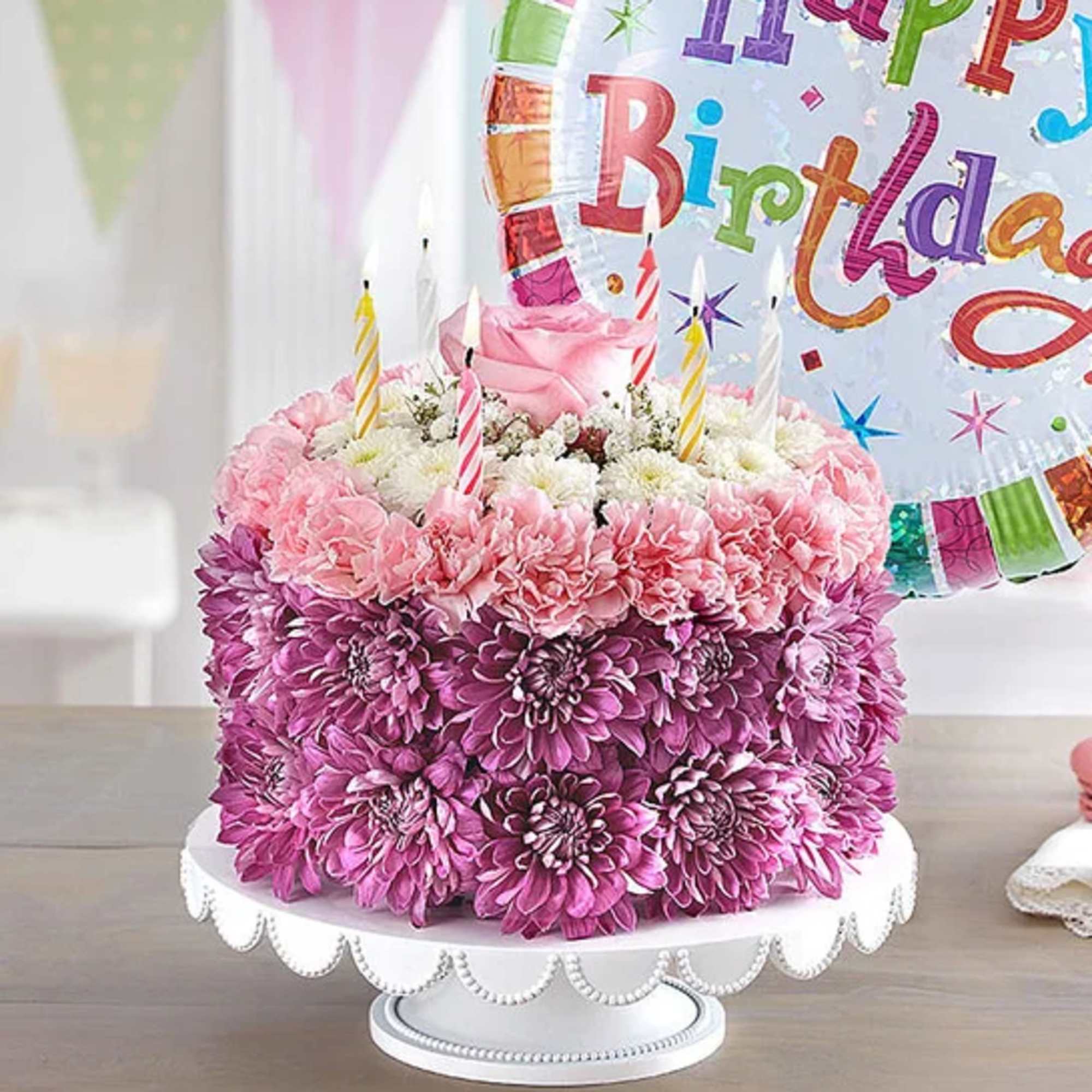 Pink and purple flower cake with birthday candles and a balloon