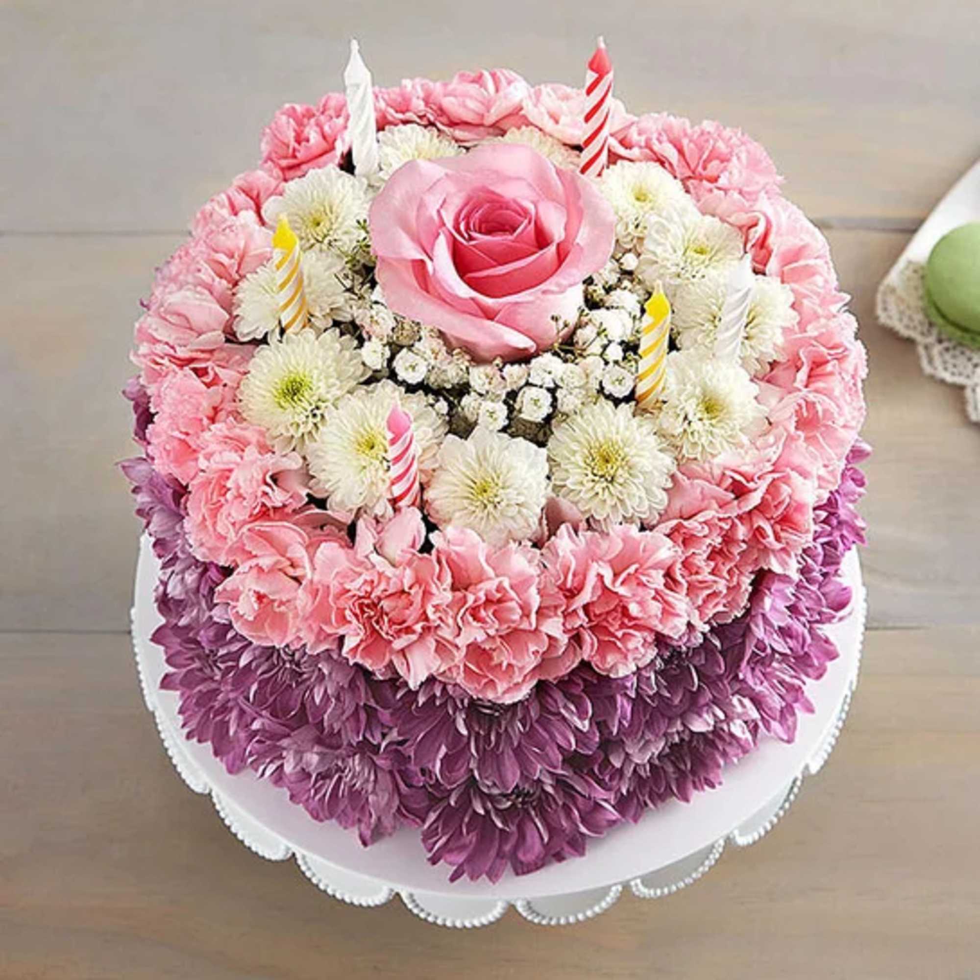 Round floral cake with pink and purple flowers and candle toppers