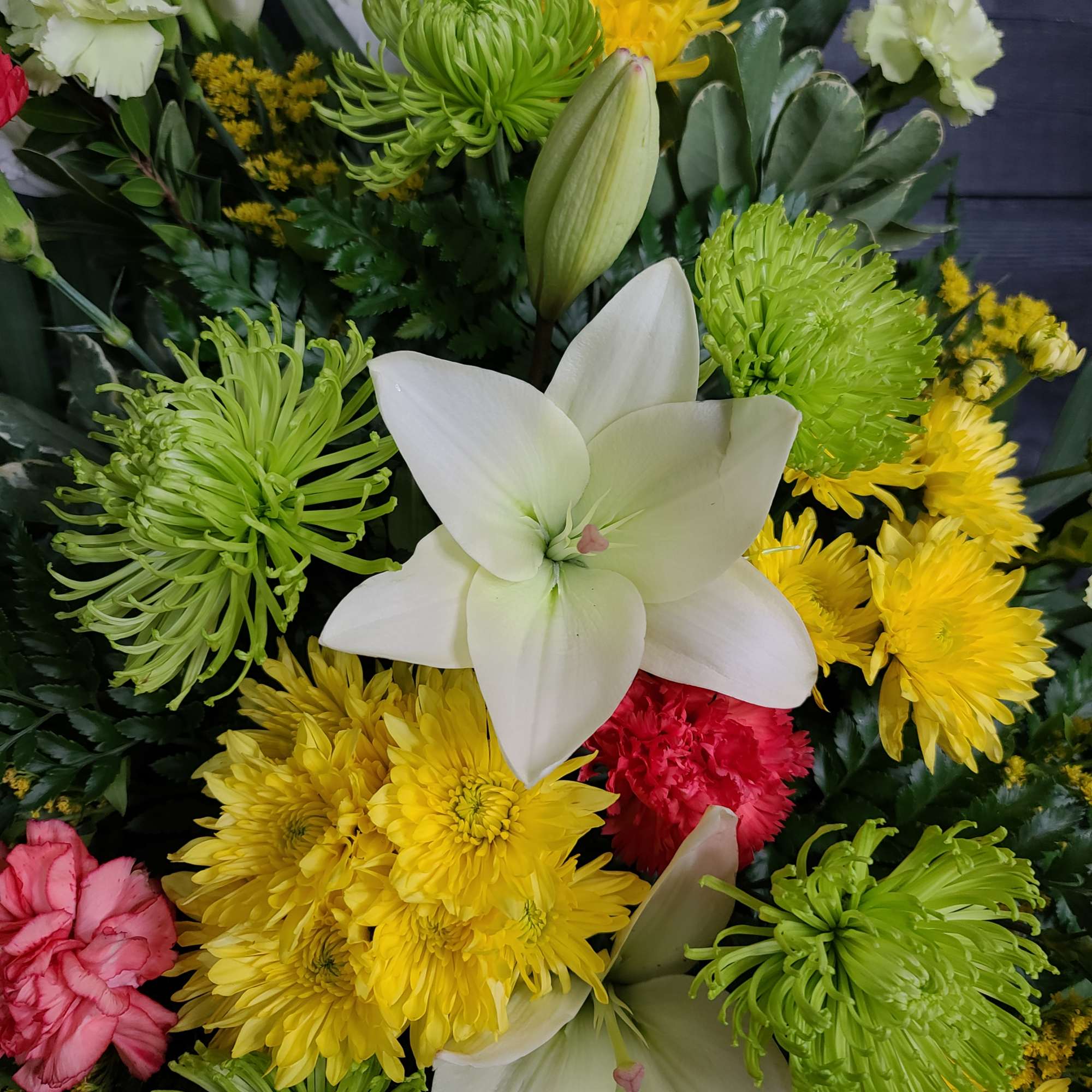 Mixed bouquet with white lilies, green spider mums, yellow chrysanthemums, and pink carnations