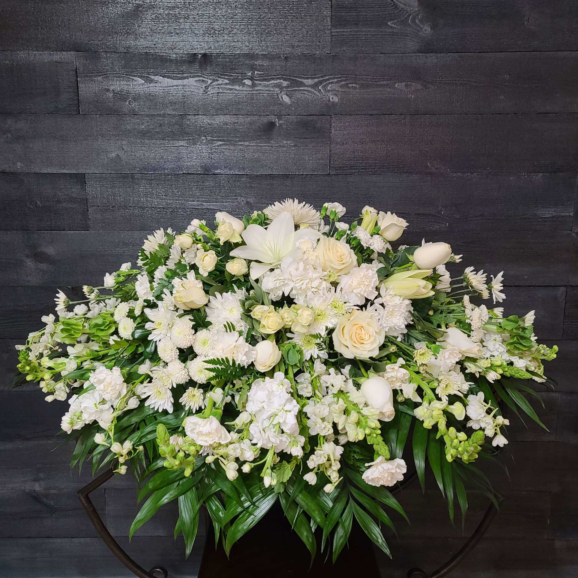 The casket spray features roses,  lilies, and many other blooms. , photo 3 of 3