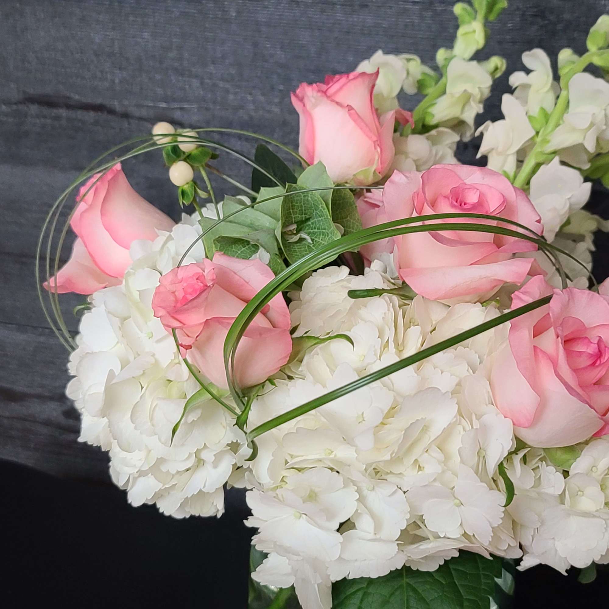 Pink roses arranged with white hydrangeas in a vase