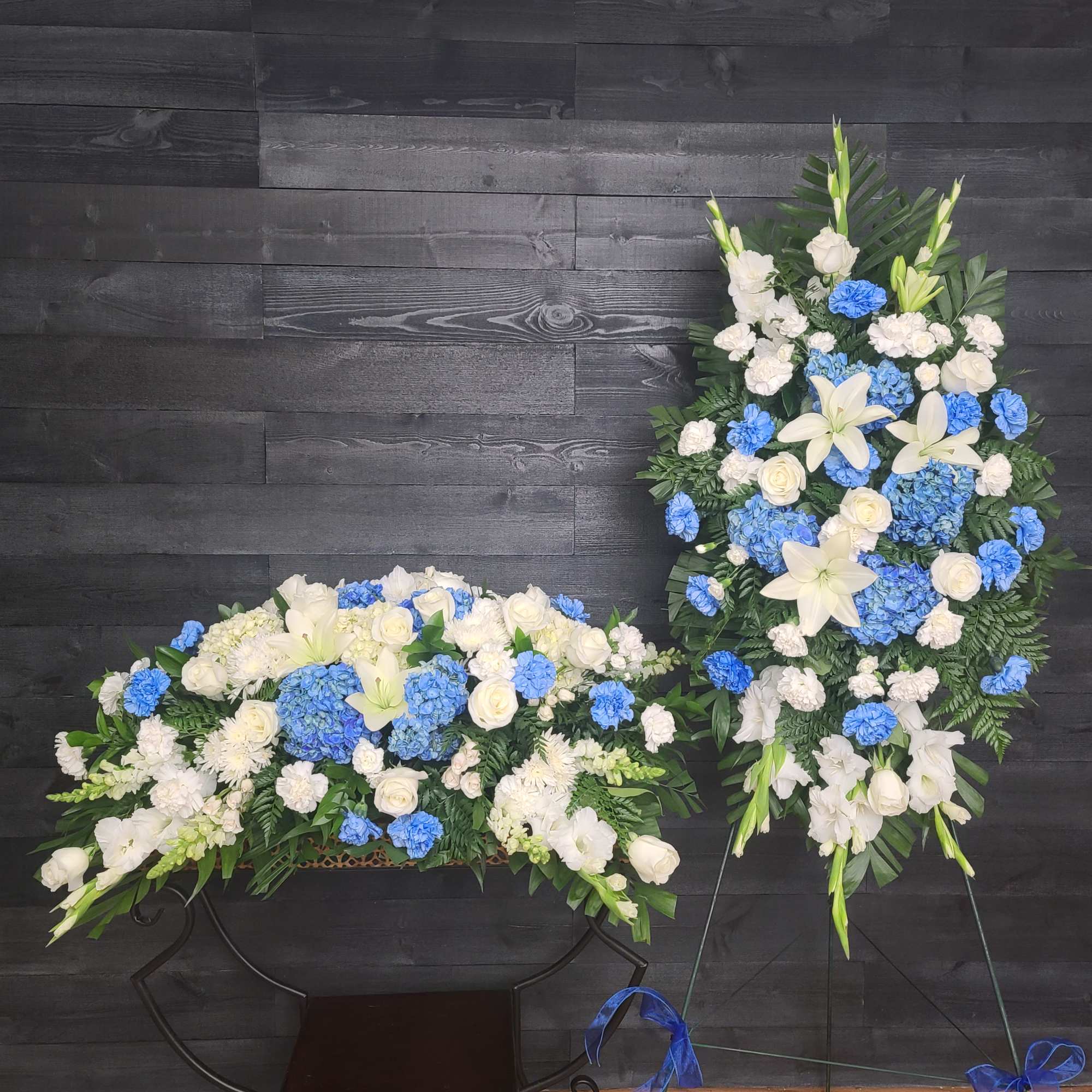 Casket Spray only. Blue delphinium, white lilies and other seasonal blooms. Approximately, photo 5 of 5