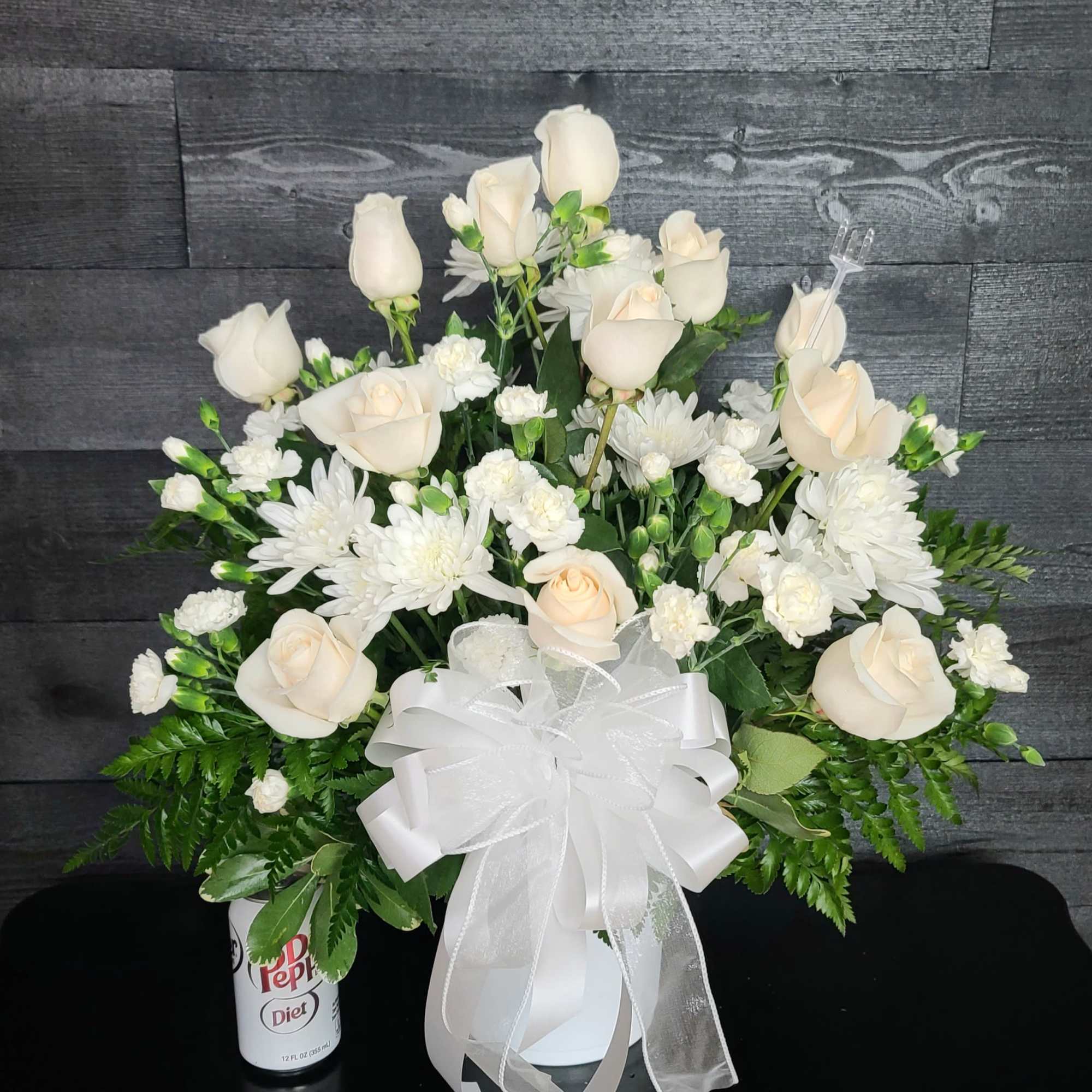White rose and chrysanthemum arrangement with a large white bow in a vase