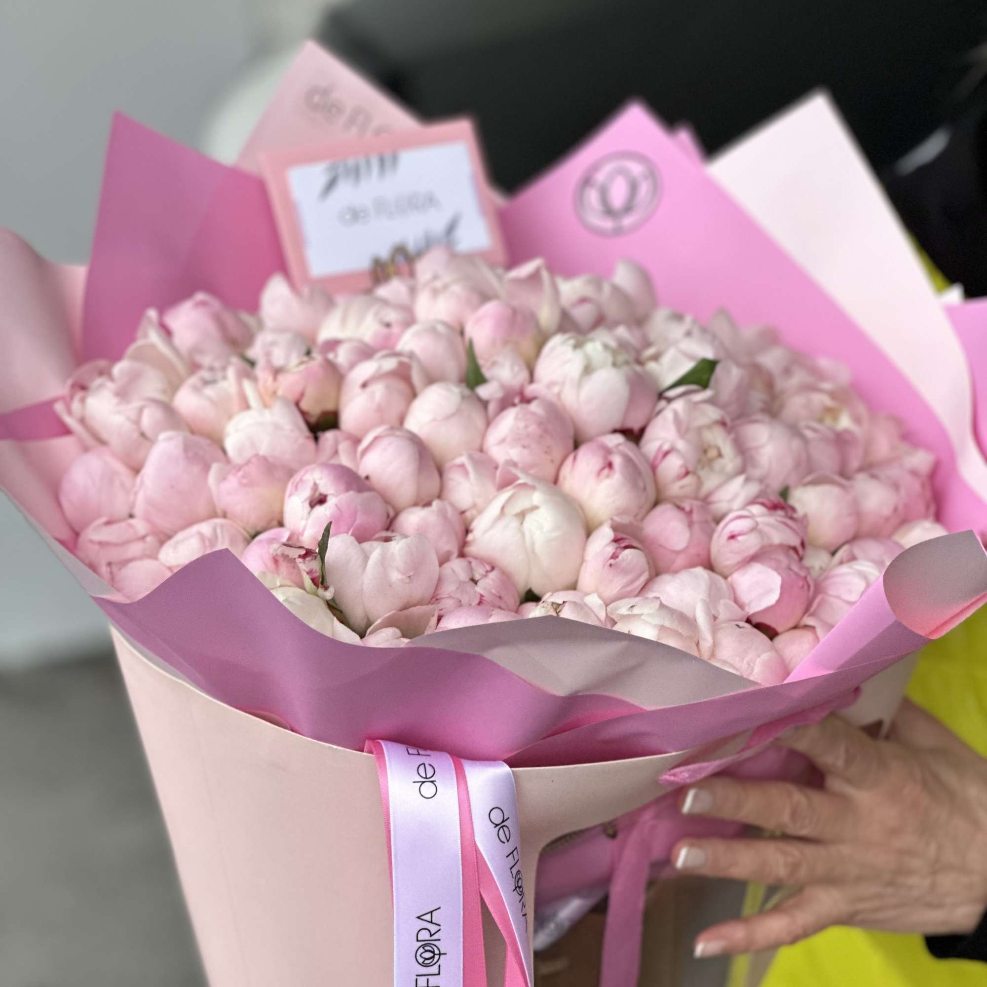 Large bouquet of pale pink peonies wrapped in pink paper