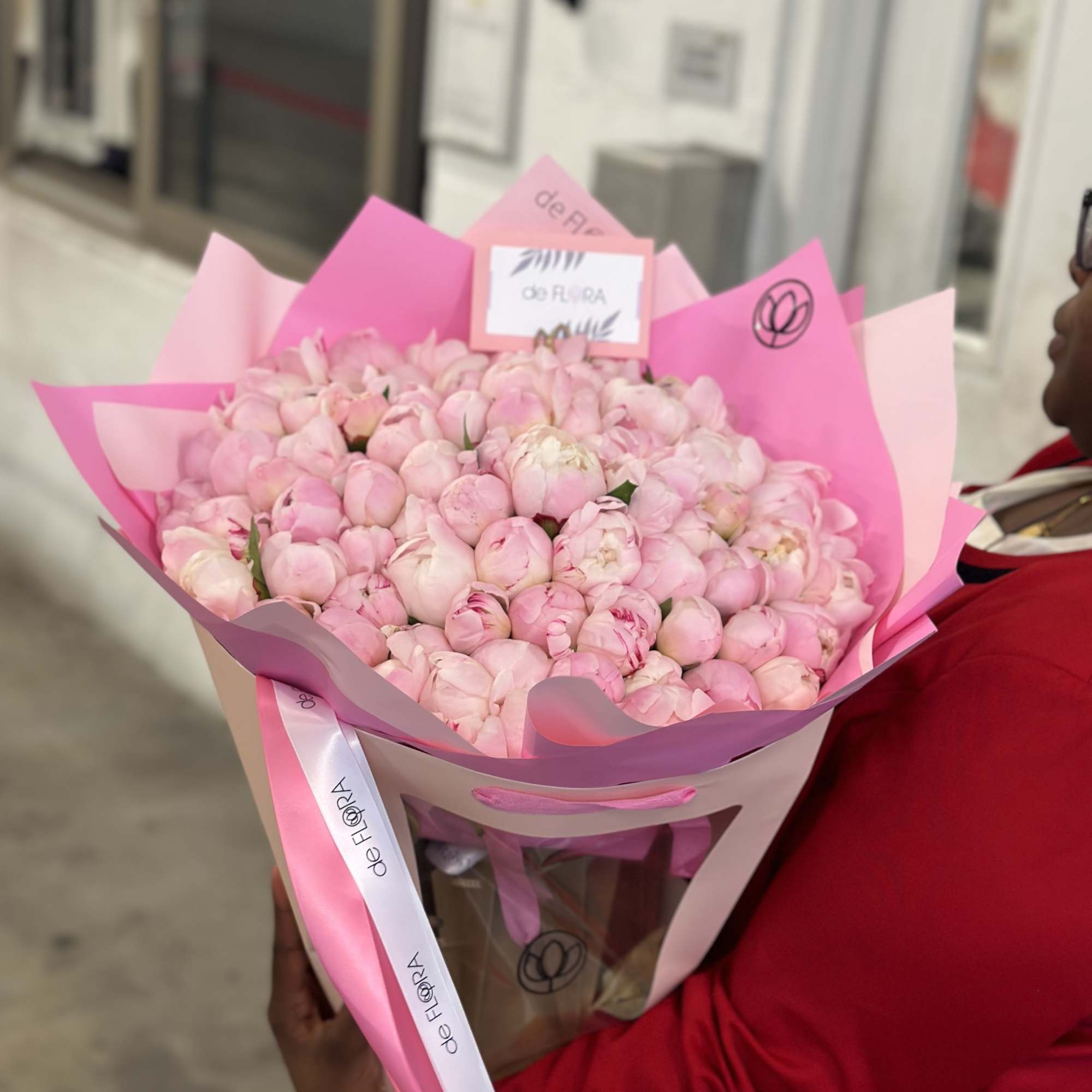 Bouquet of pale pink peonies wrapped in pink paper