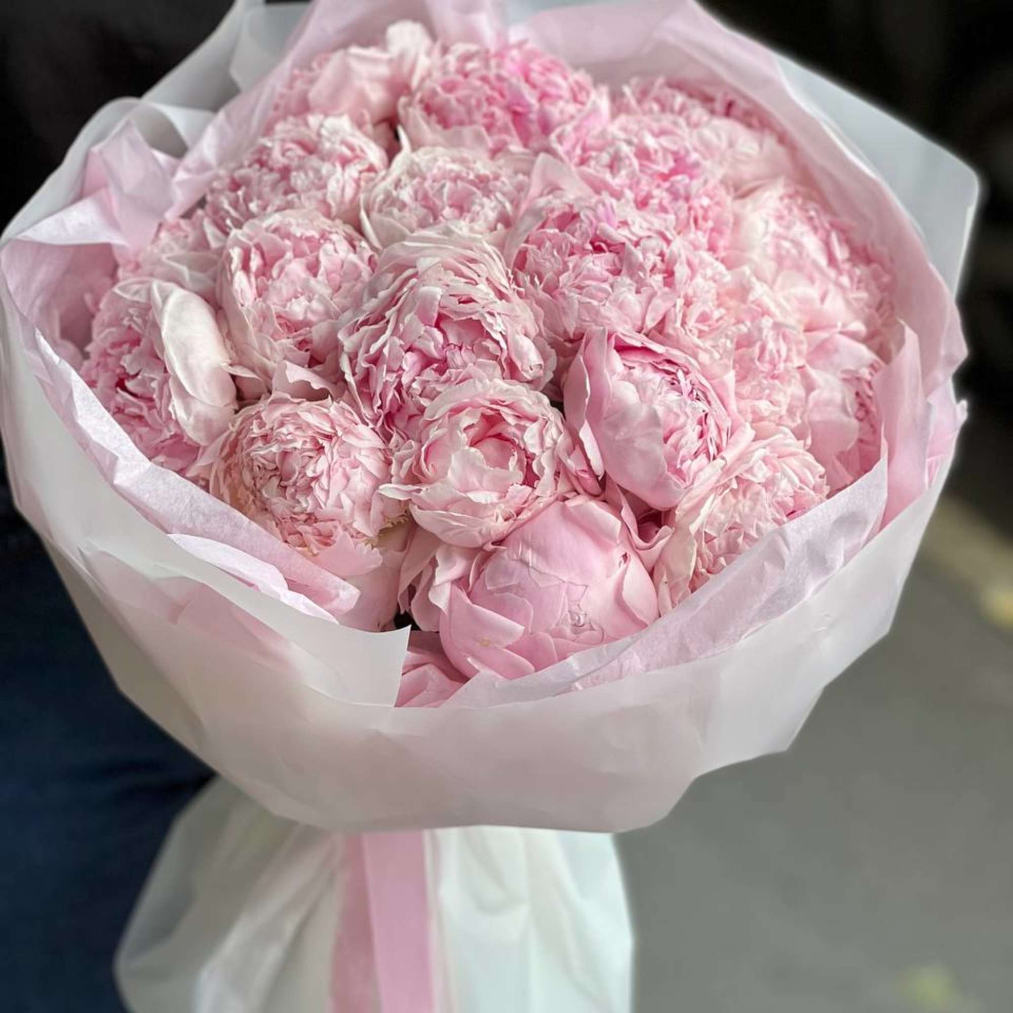 Bouquet of pale pink peonies wrapped in white paper