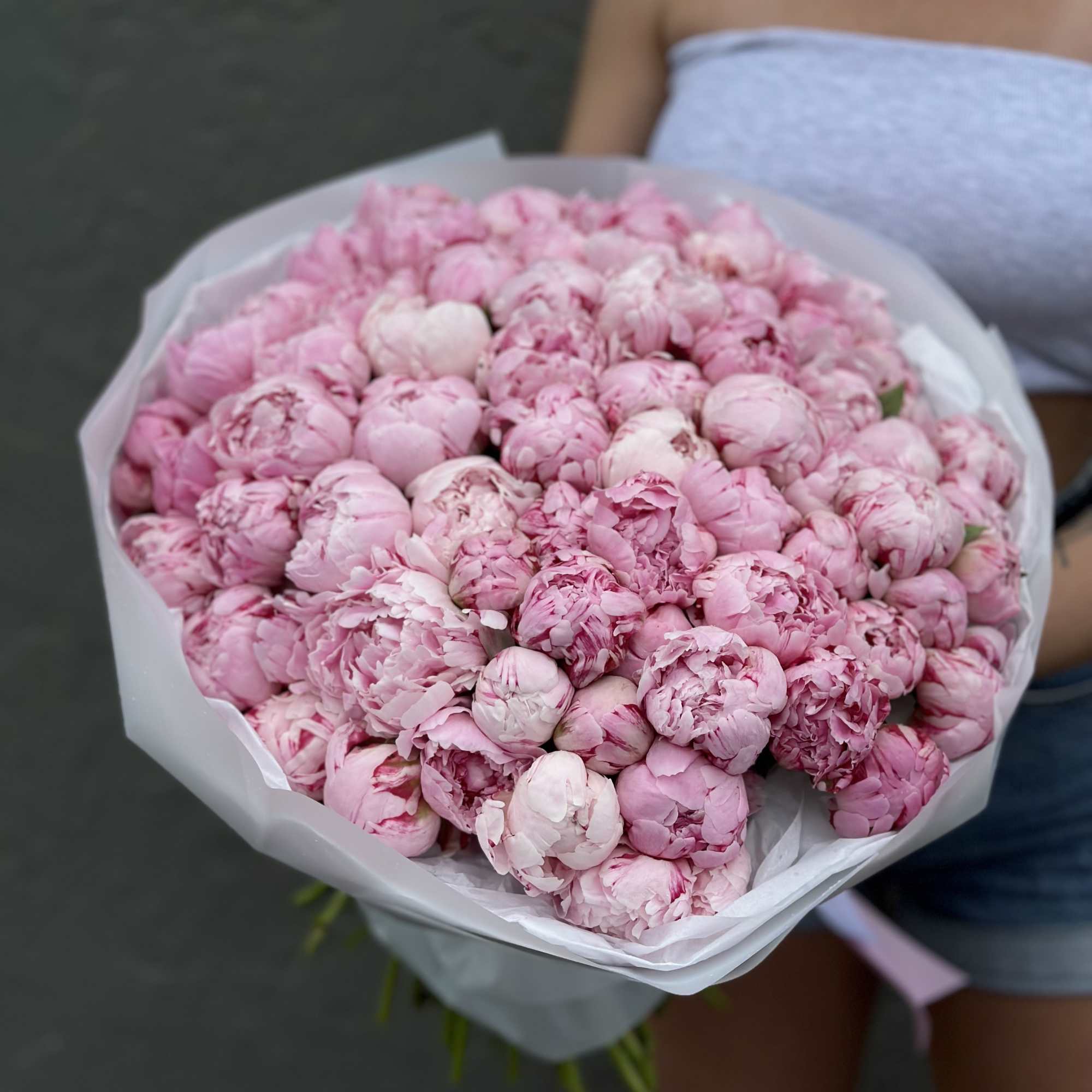 Large bouquet of pink peonies wrapped in white paper