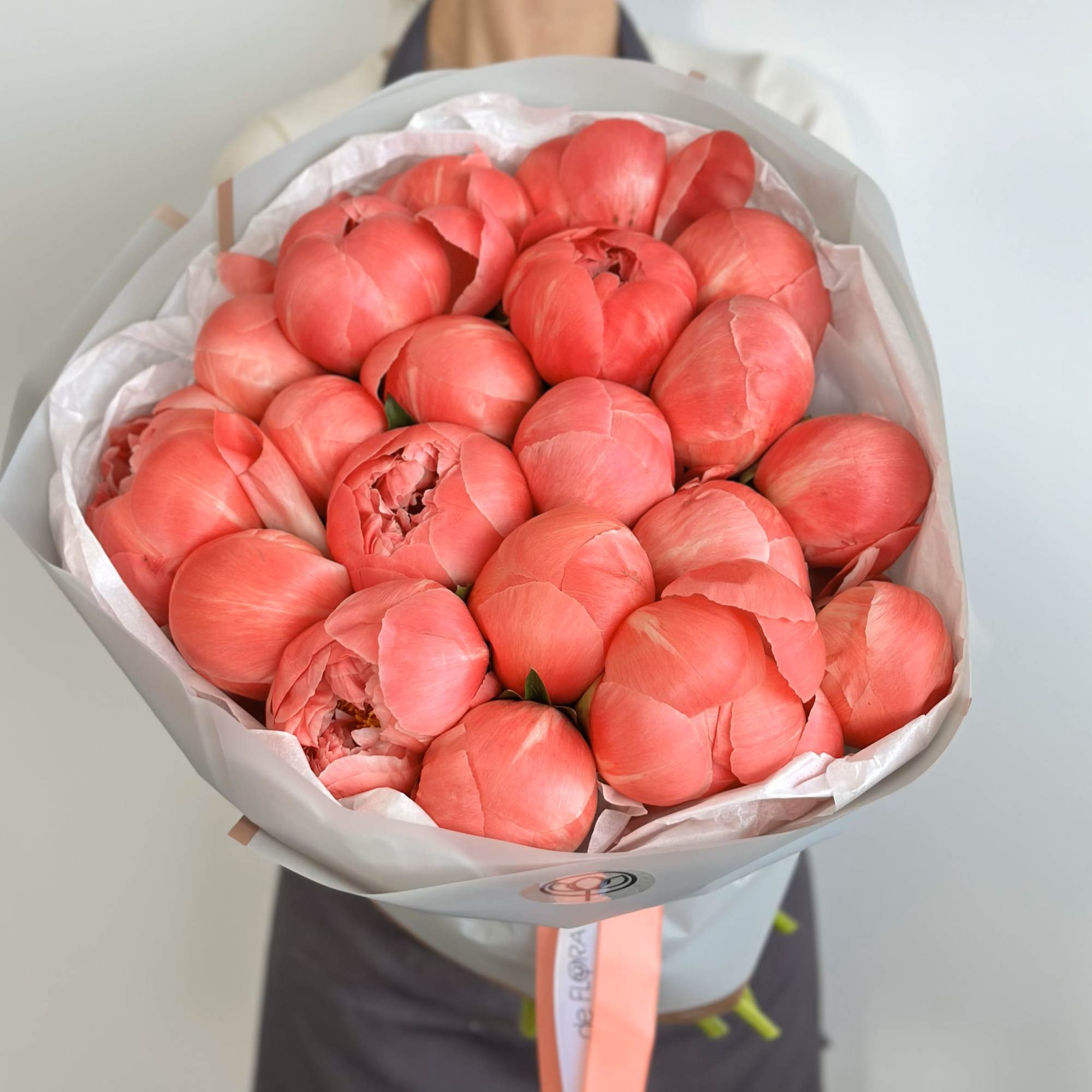Bouquet of coral-pink peonies wrapped in pale paper