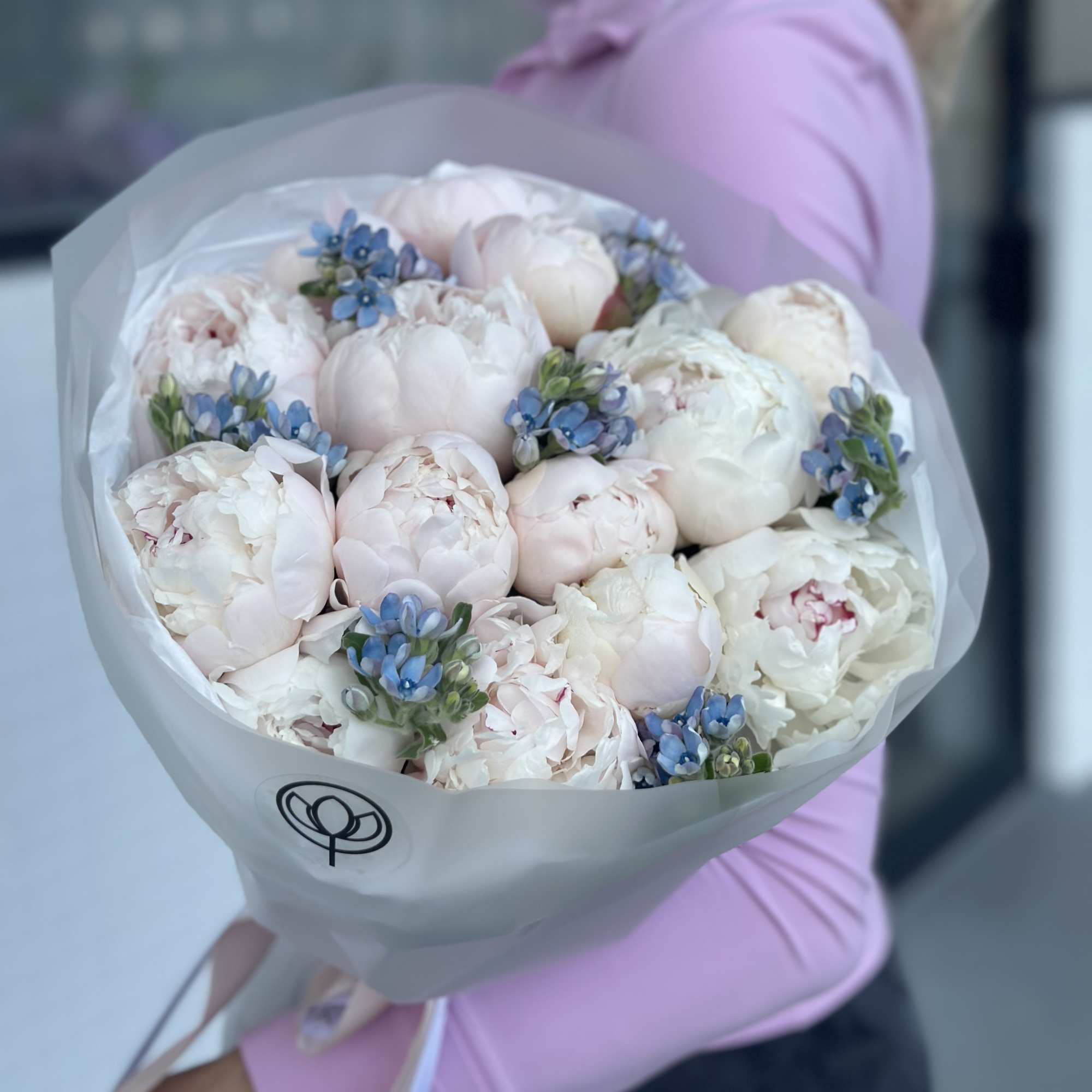 Bouquet of pale pink and white peonies with small blue flowers