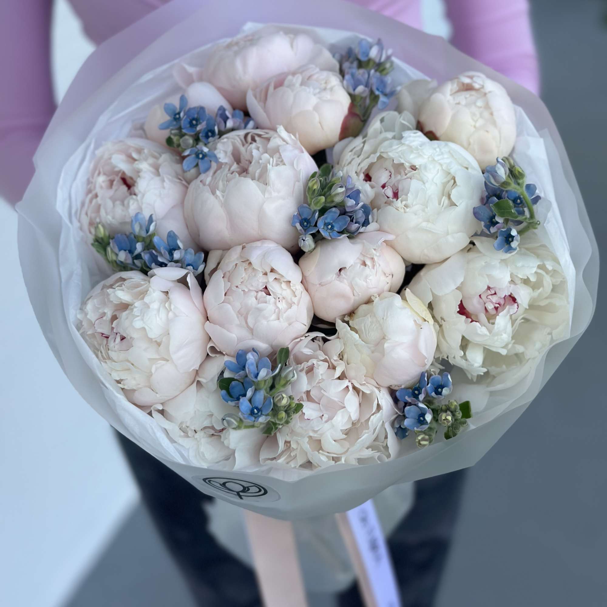 Bouquet of pale pink and white peonies with small blue flowers