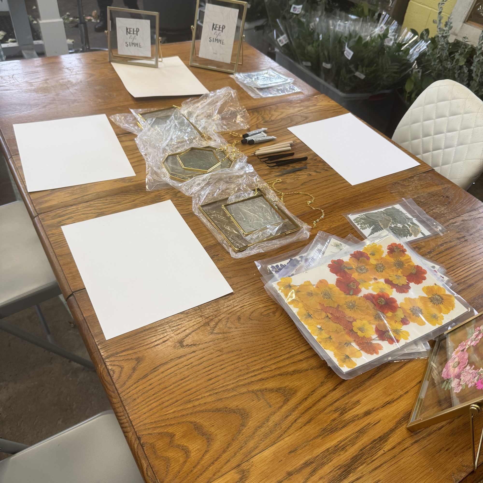 Craft supplies and framed floral pieces arranged on a wooden table