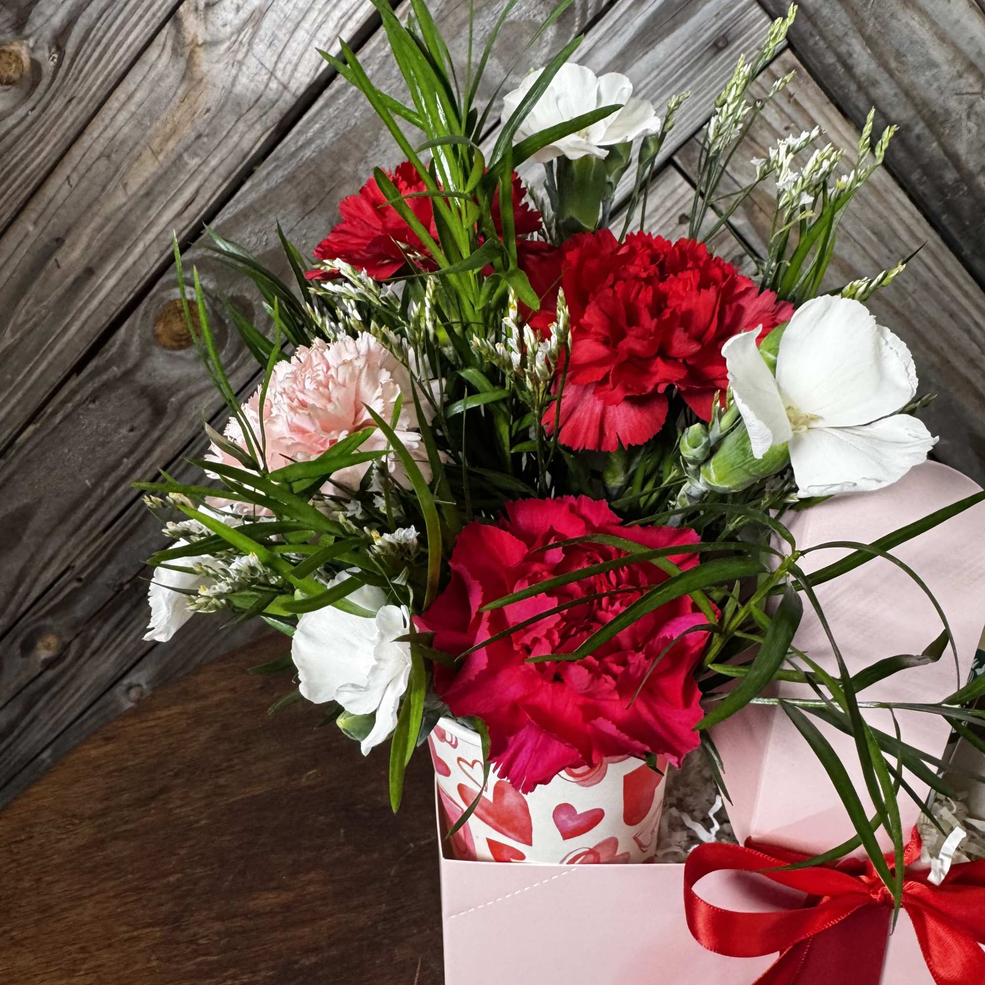 Bouquet of red and white carnations in a pink gift box