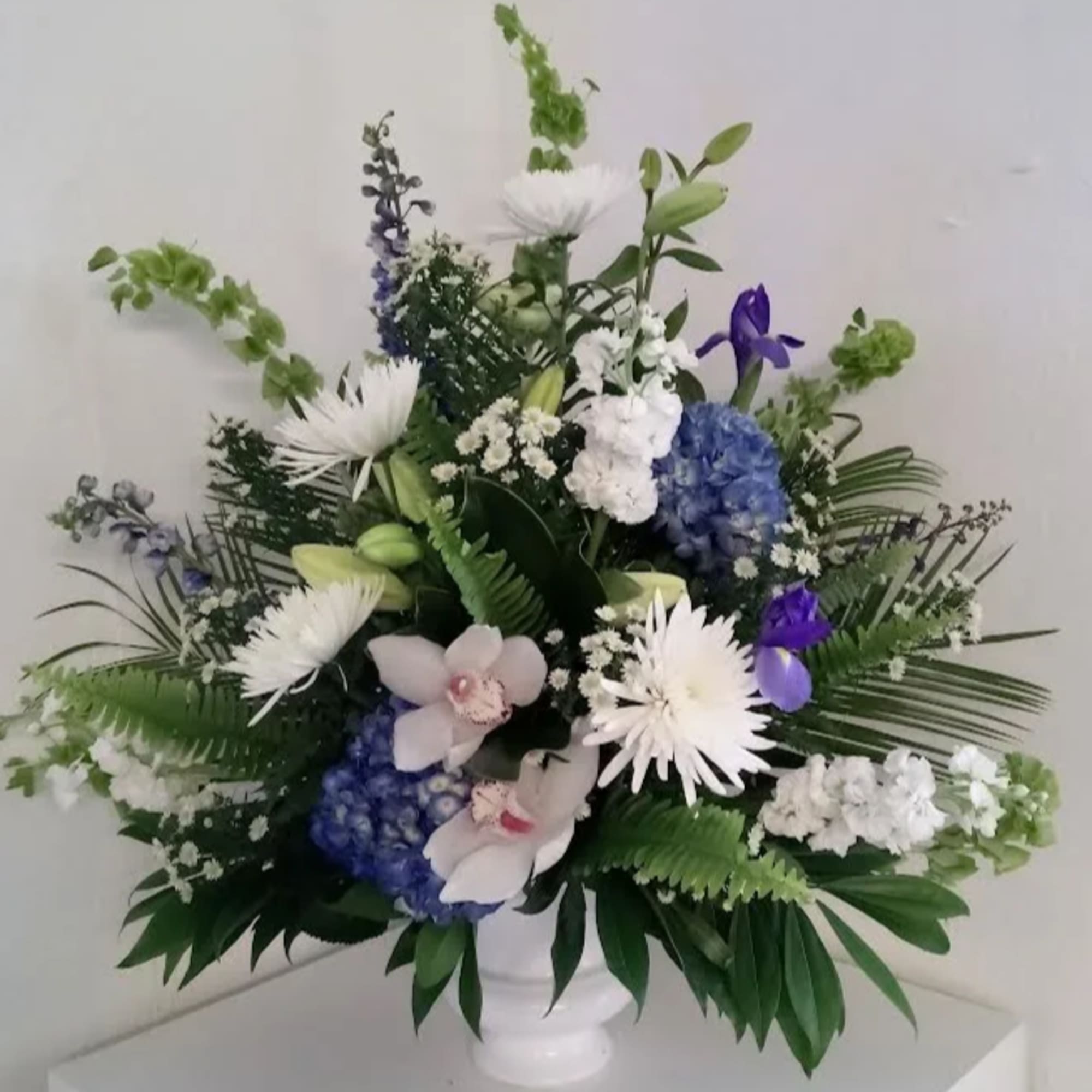 White and blue floral arrangement in a white vase