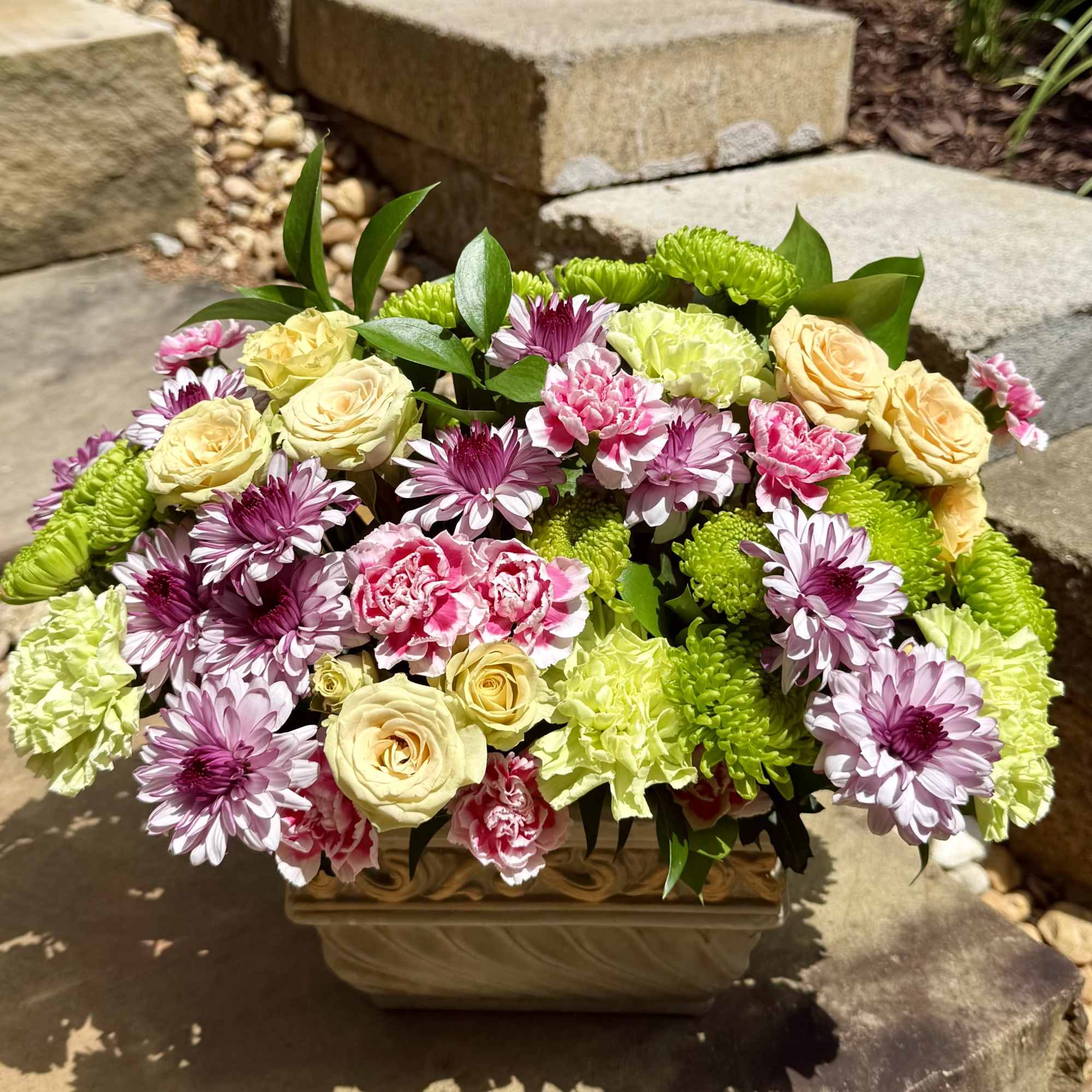 A lush blend of roses, carnations, and daisies in soft pastels and