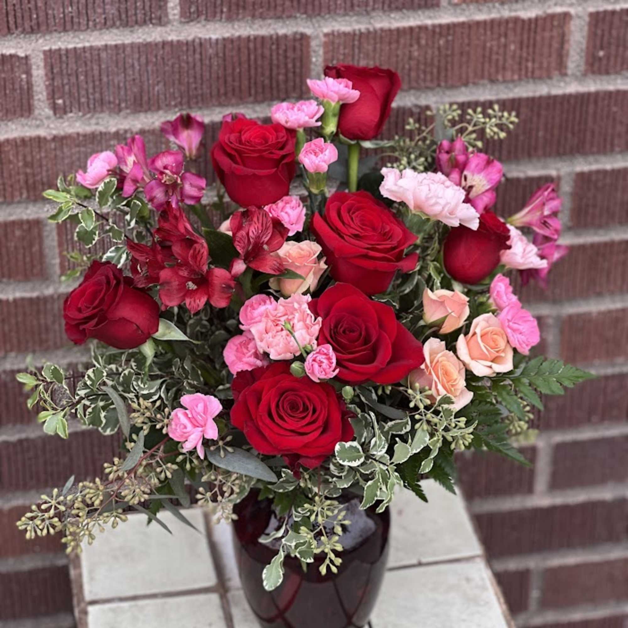 Bouquet of red and pink roses in a dark vase