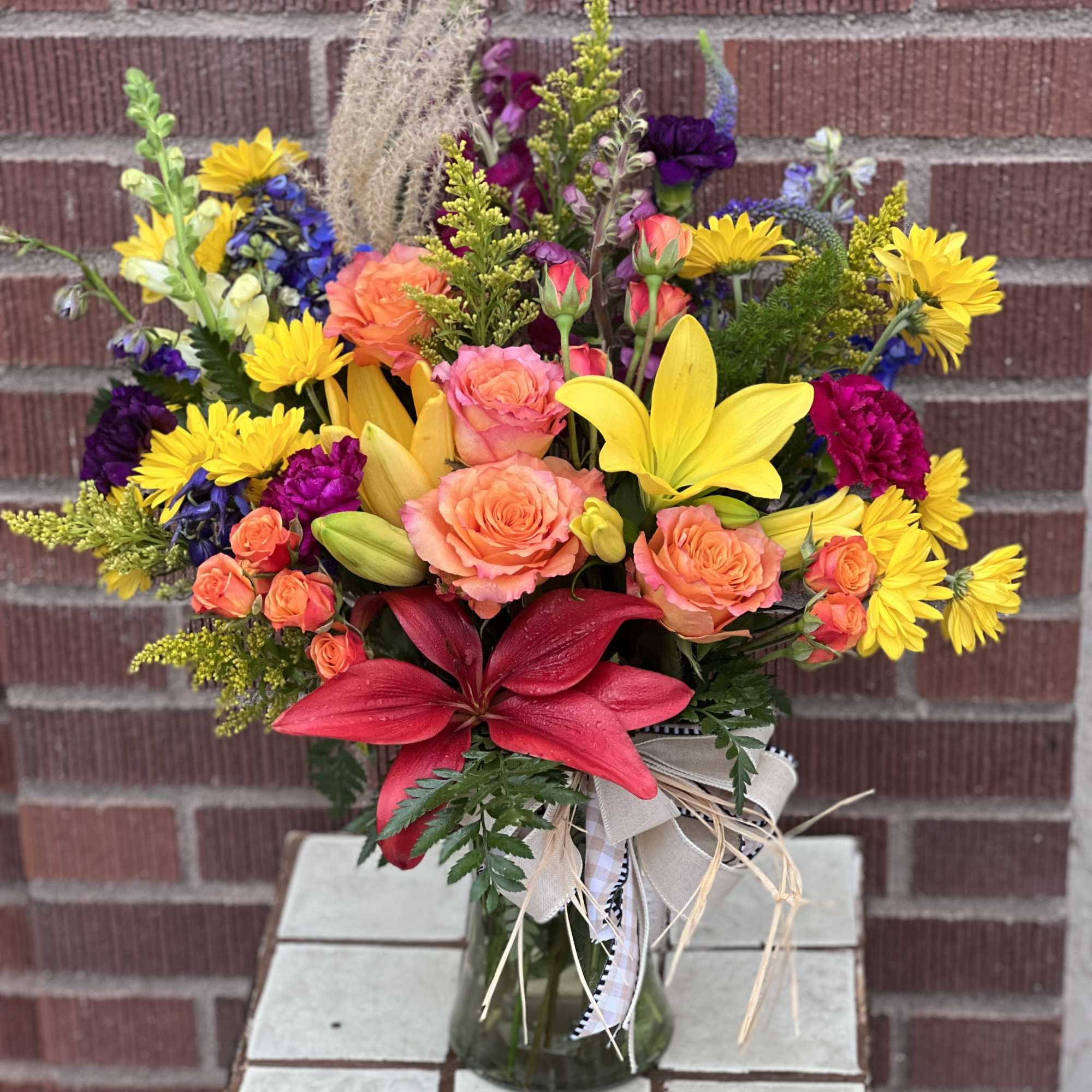Colorful mixed bouquet in a glass vase with lilies and roses