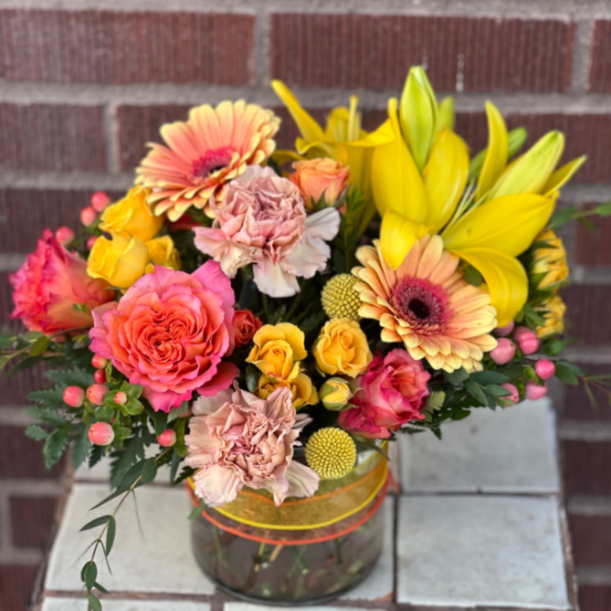 Mixed bouquet in a glass vase with pink, yellow, and peach flowers