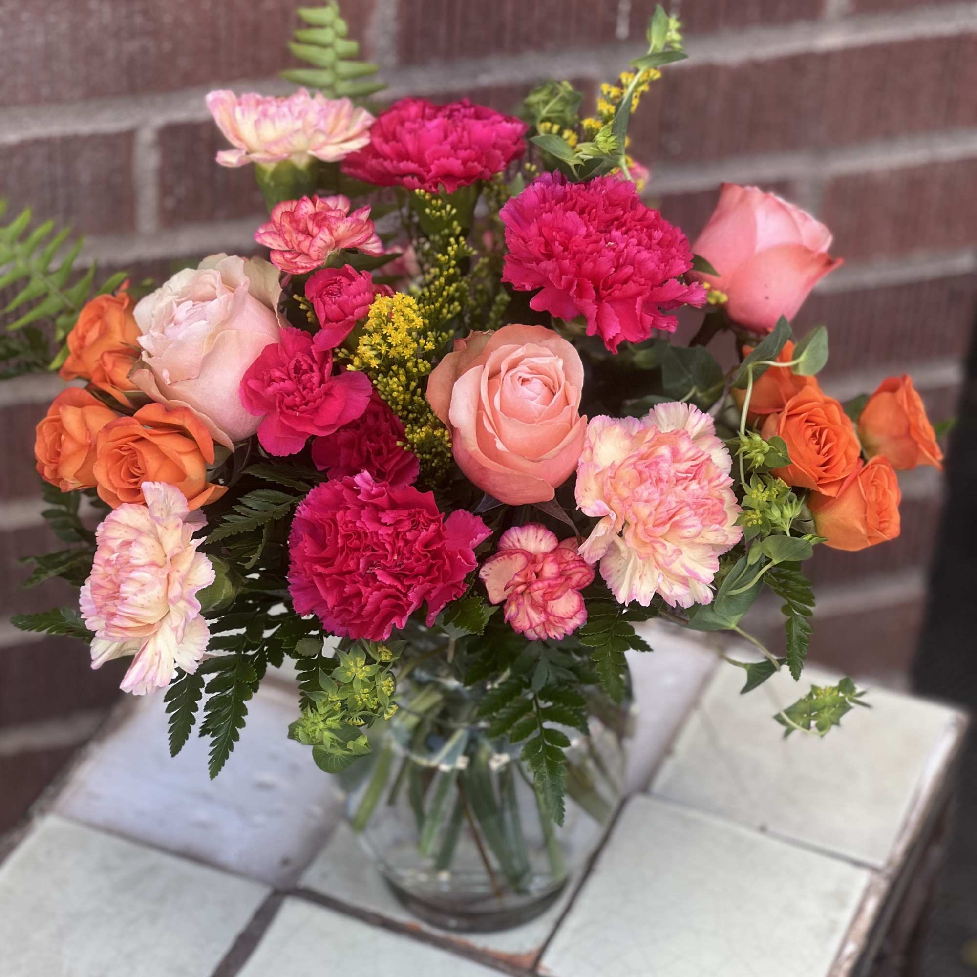 Bouquet of pink and orange roses with carnations in a glass vase