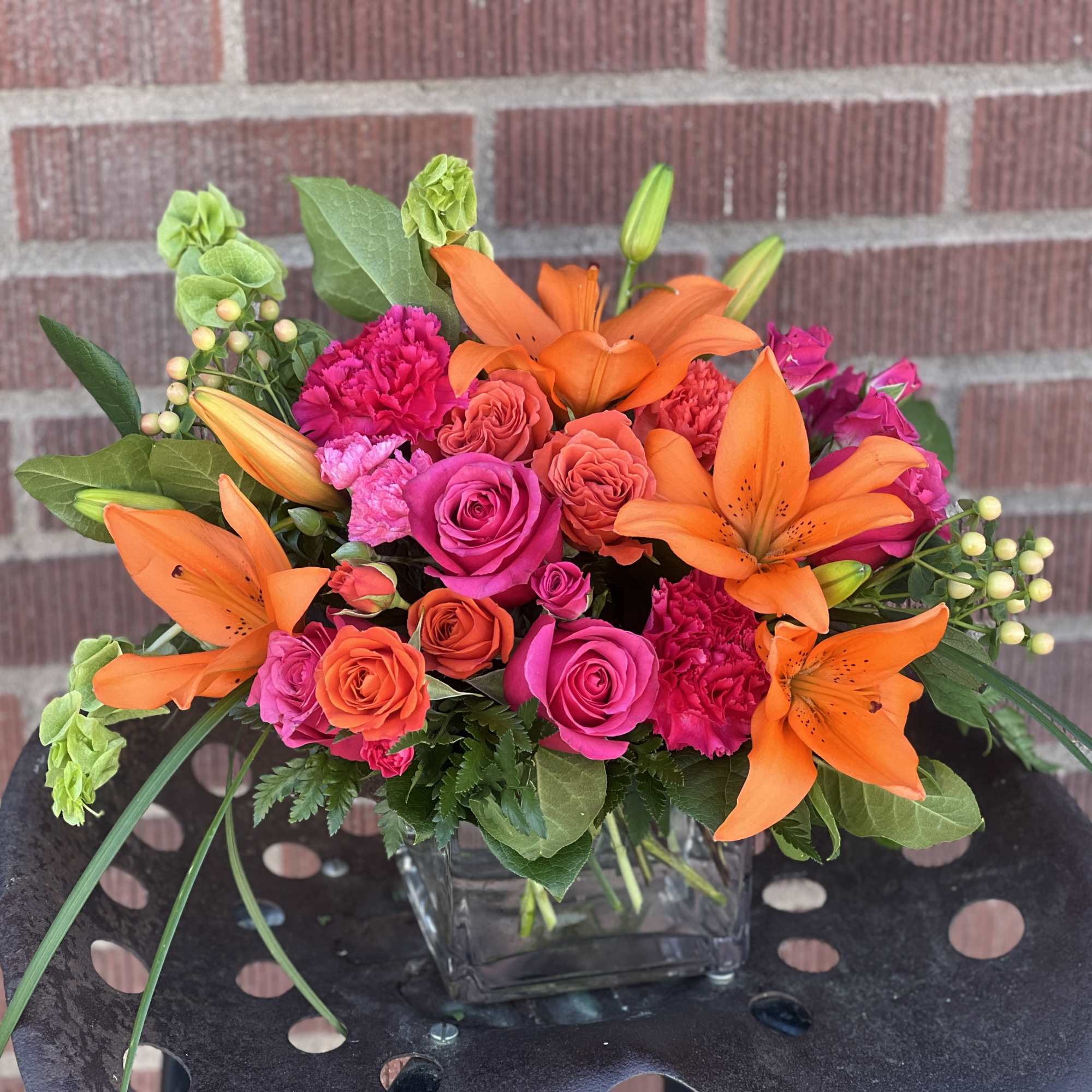 Orange lilies and pink roses in a glass vase