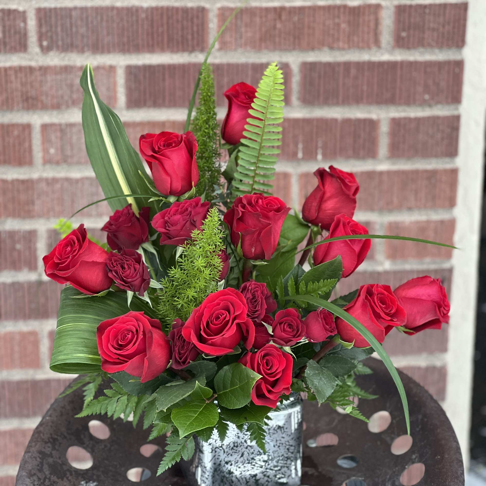 Red rose arrangement in a silver square vase