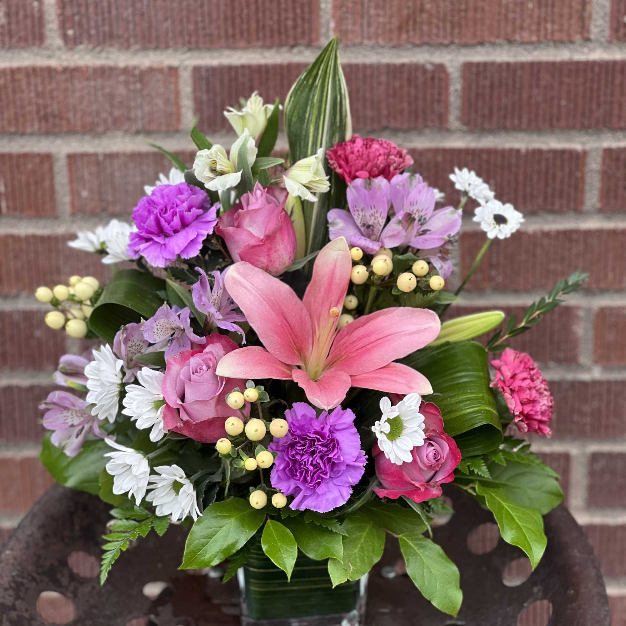 Mixed bouquet in a glass vase with pink lilies, roses, and purple carnations
