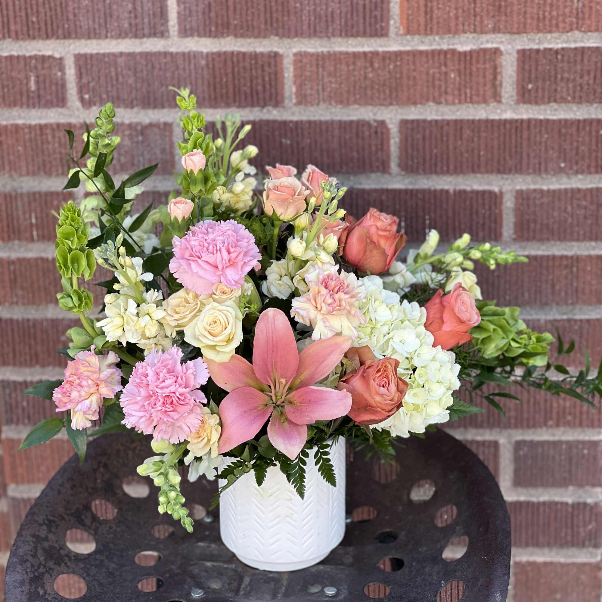 Pink and peach floral arrangement in a white vase