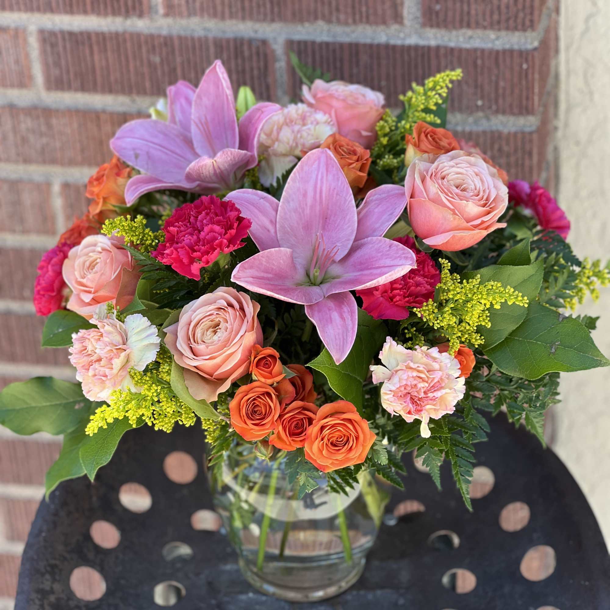 Bouquet of pink lilies, roses, and carnations in a glass vase