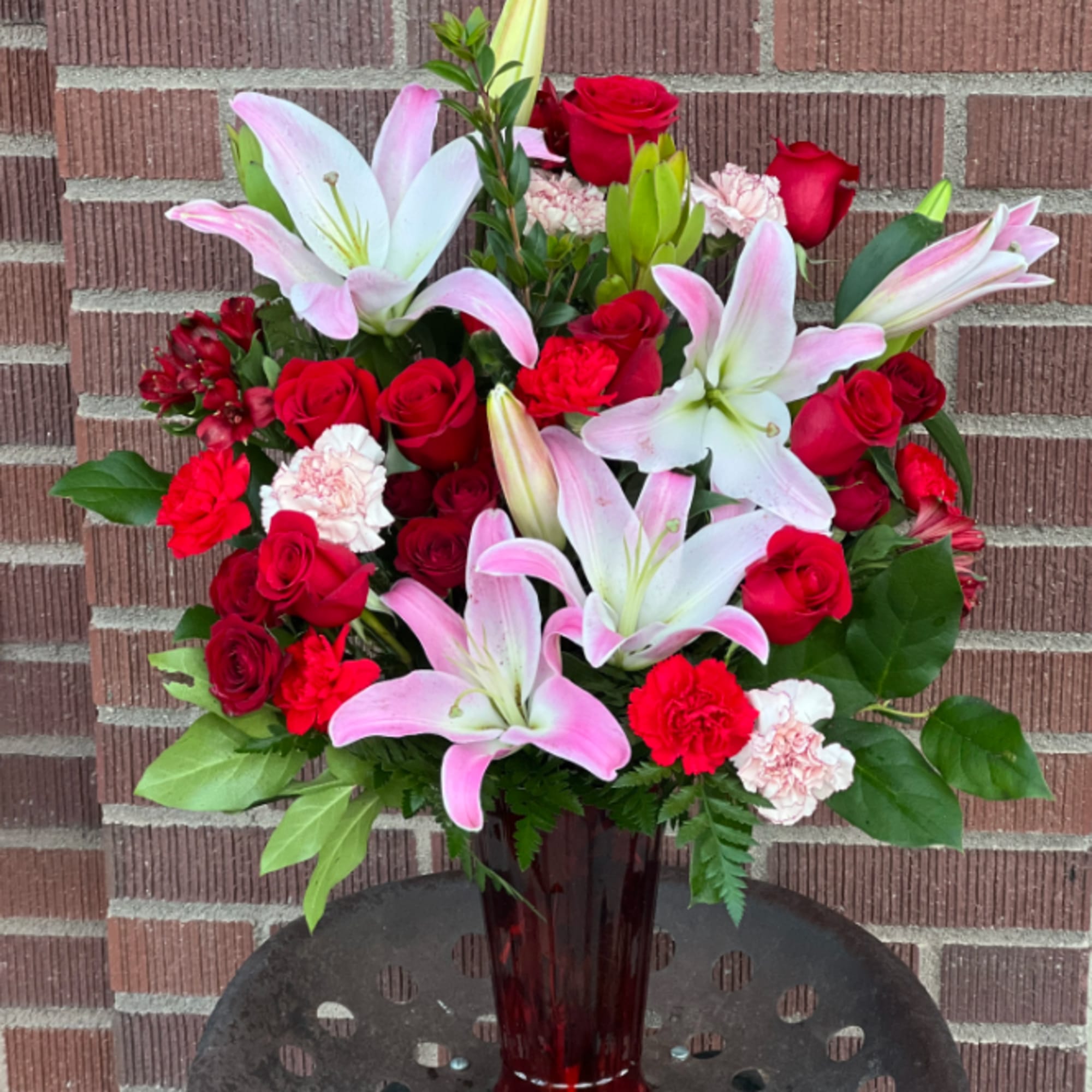 Red roses and pink lilies arranged in a tall glass vase