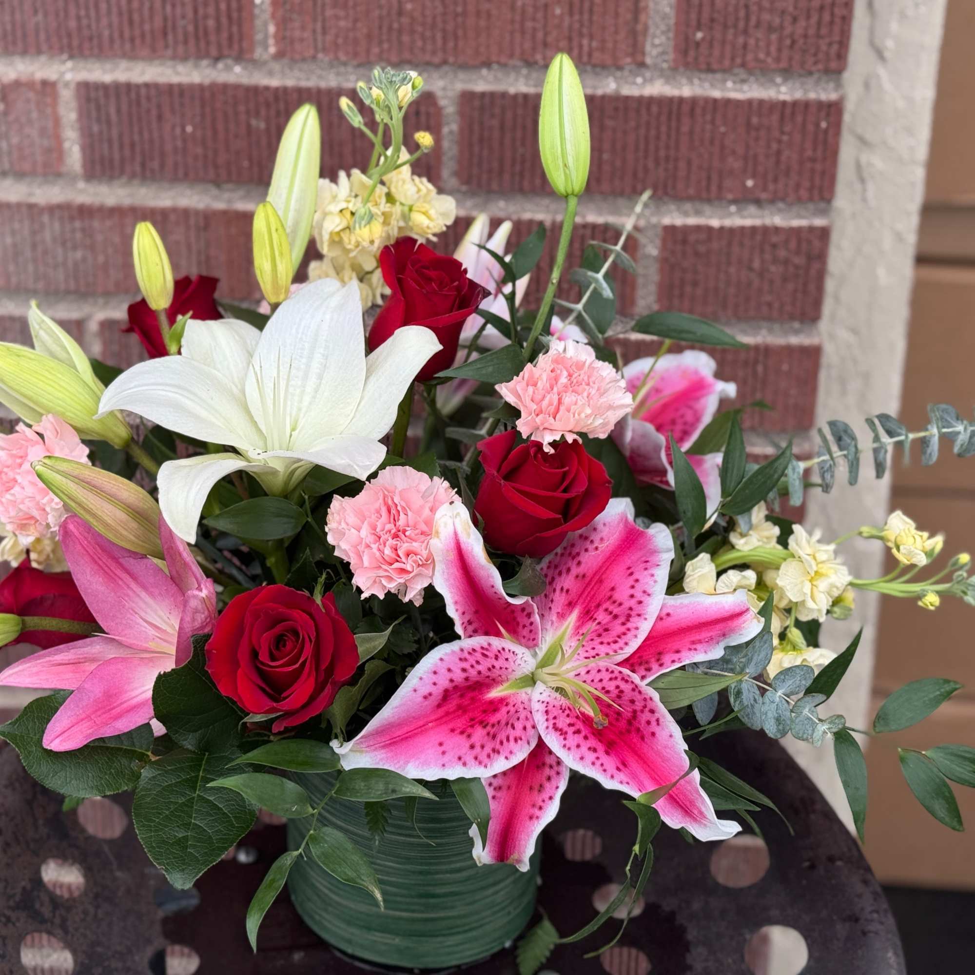 Mixed bouquet of red roses, pink and white lilies, and carnations in a vase
