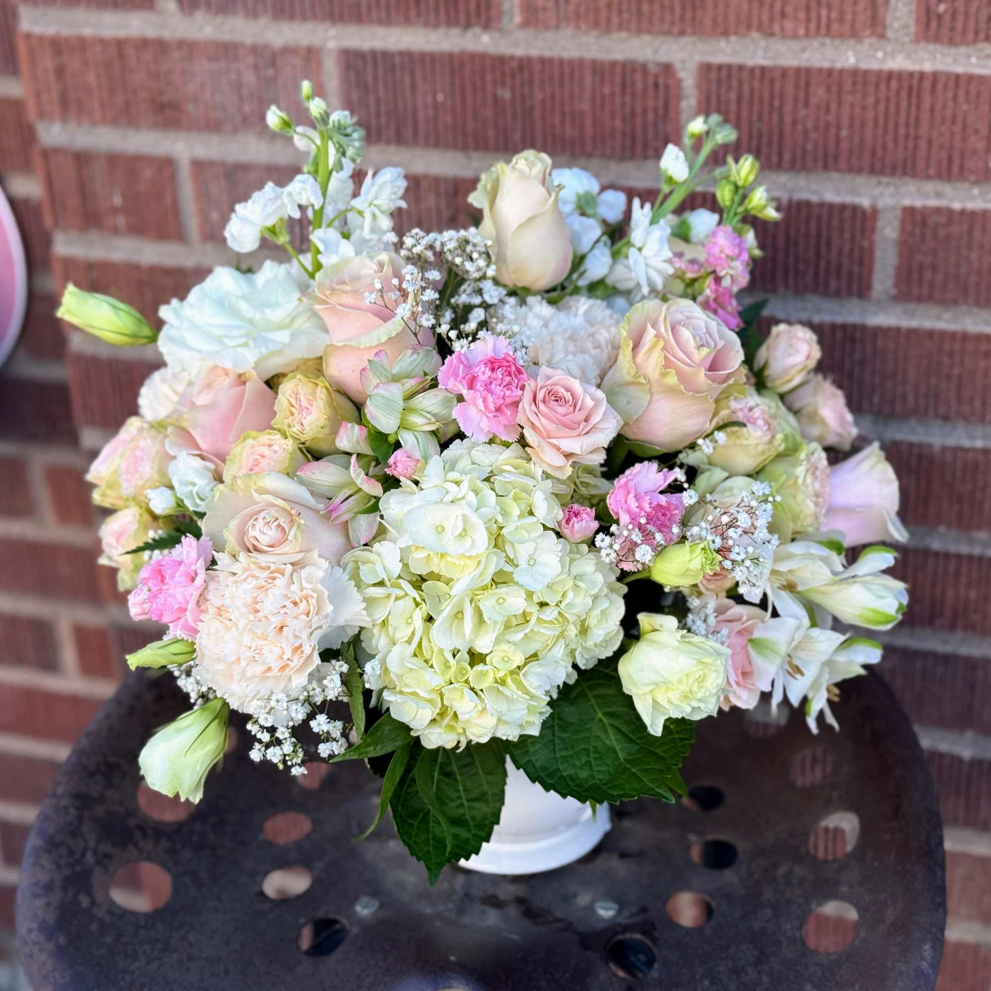 Pastel bouquet of roses, hydrangea, and carnations in a white vase