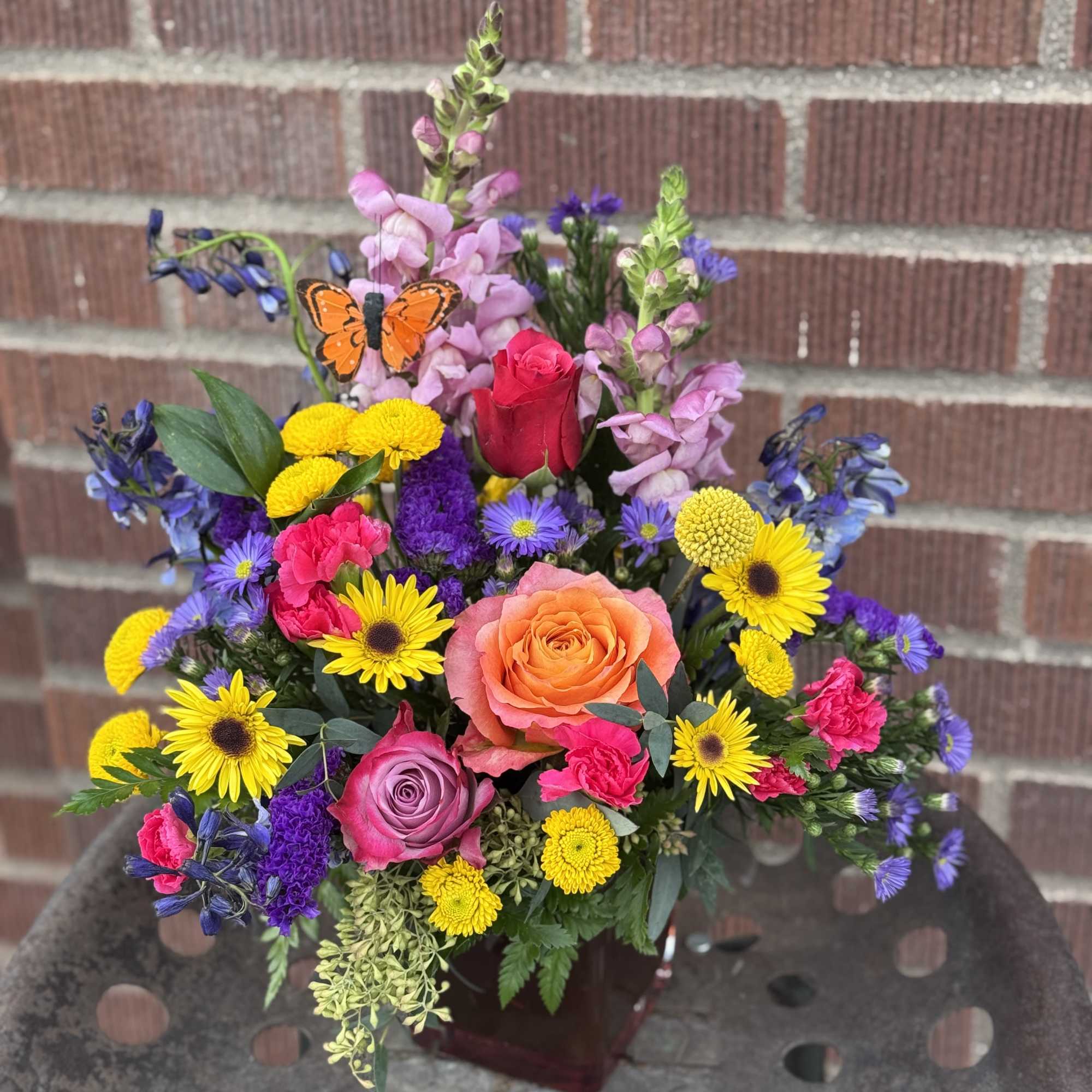 Colorful mixed bouquet with roses, daisies, and snapdragons in a vase