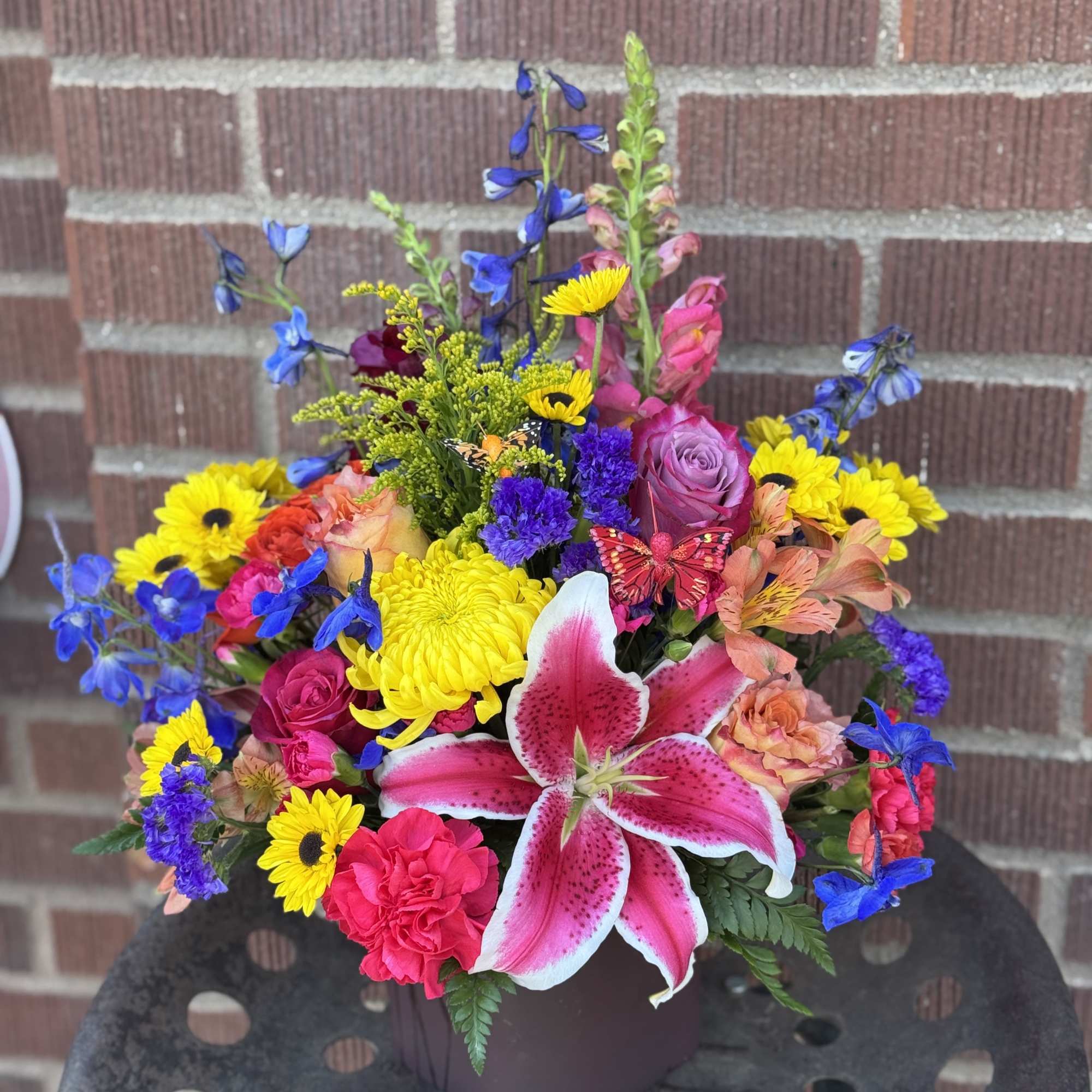 Colorful mixed bouquet with pink lilies and yellow daisies in a dark vase