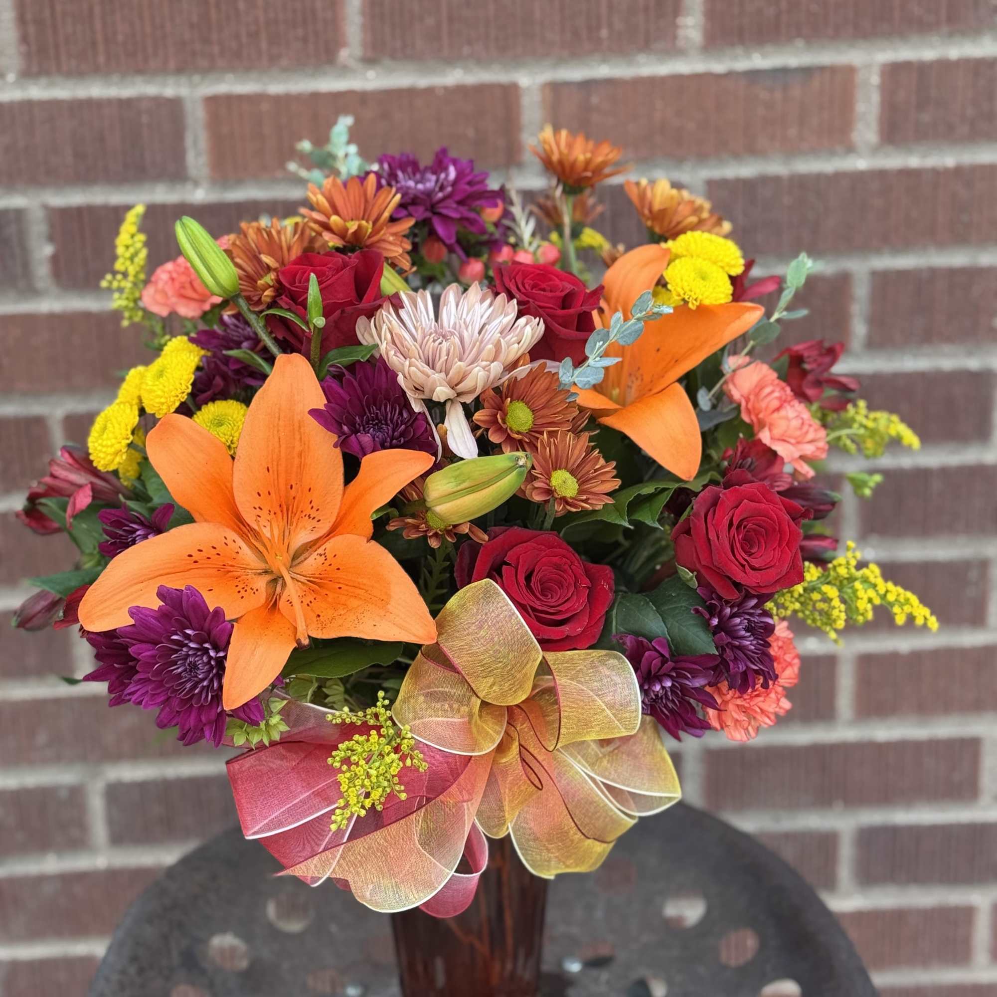 Mixed bouquet with orange lilies and red roses in a glass vase