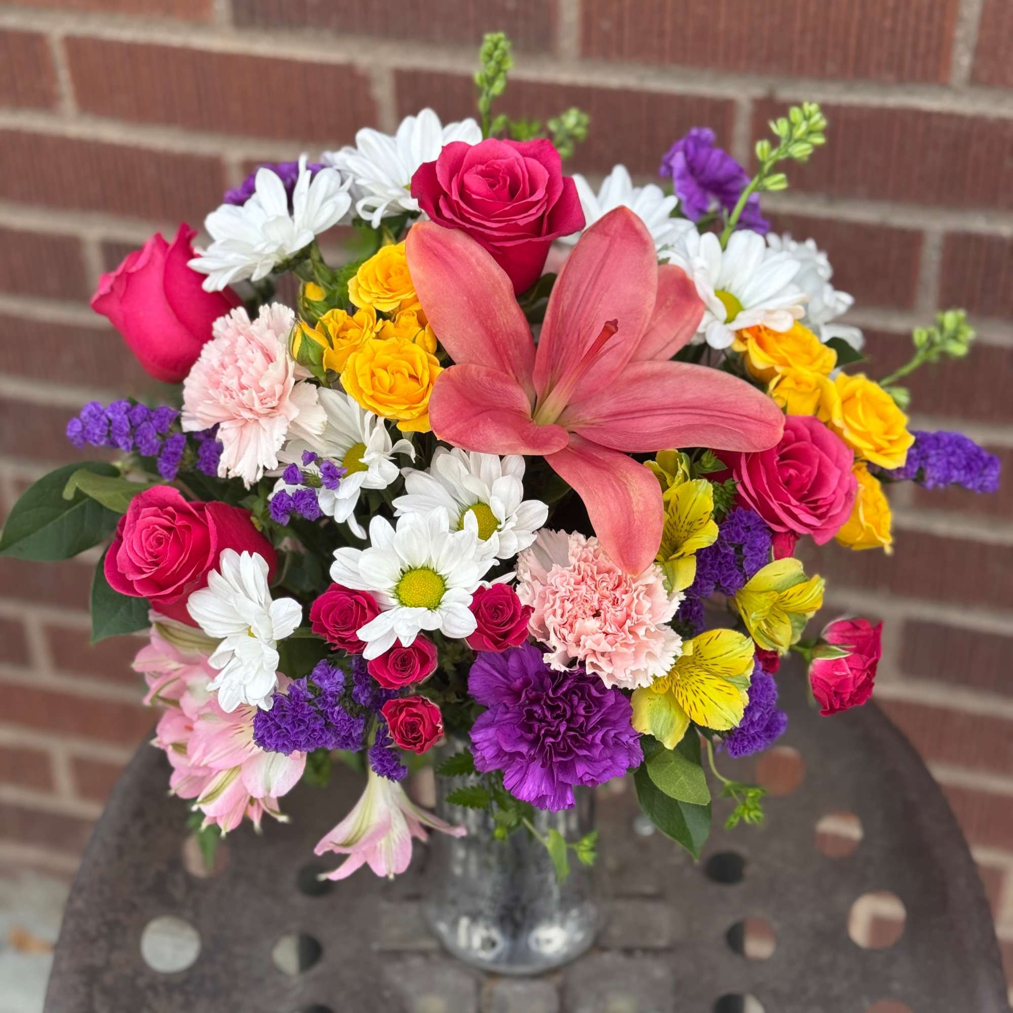 Mixed bouquet with pink roses, white daisies, and a pink lily in a glass vase
