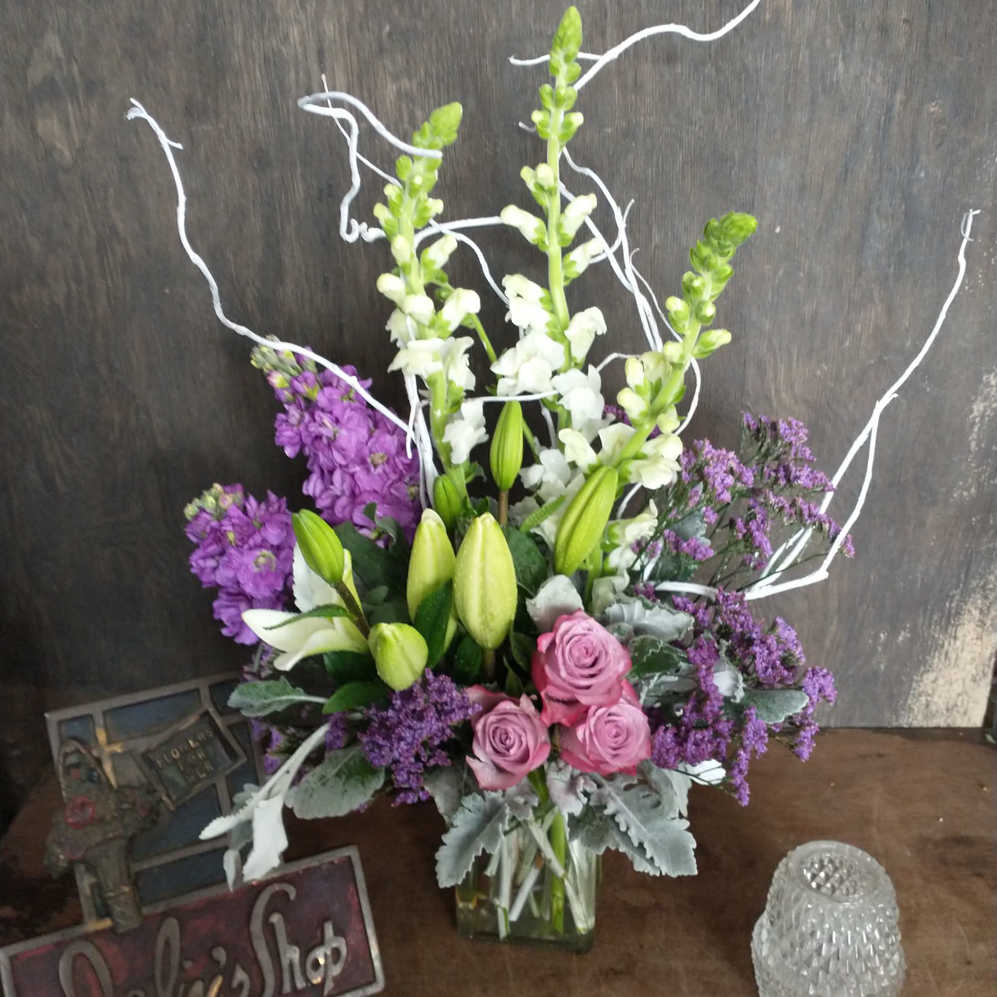 Mixed bouquet with pink roses, white lilies, and purple flowers in a glass vase