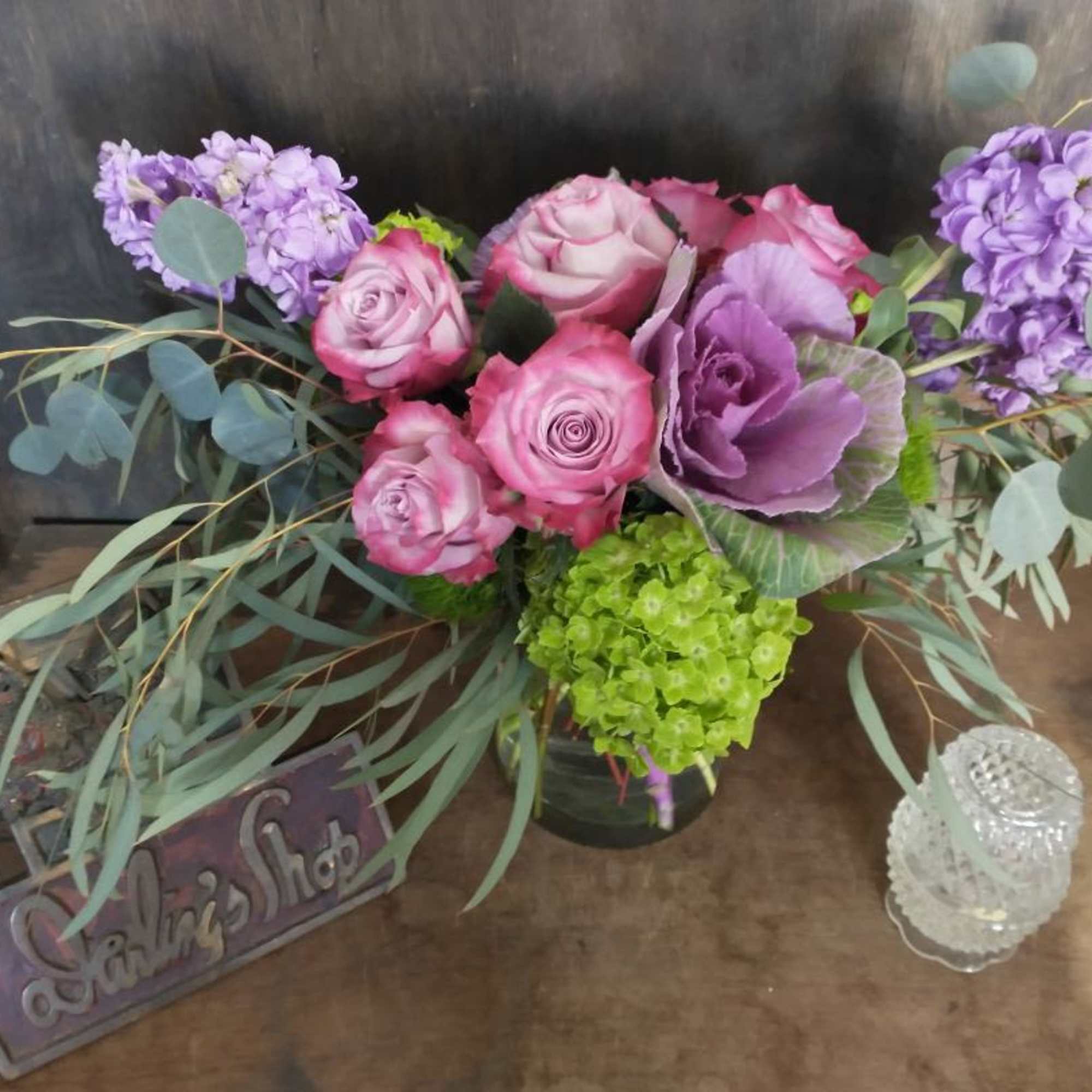 Pink roses and purple flowers arranged in a vase with eucalyptus