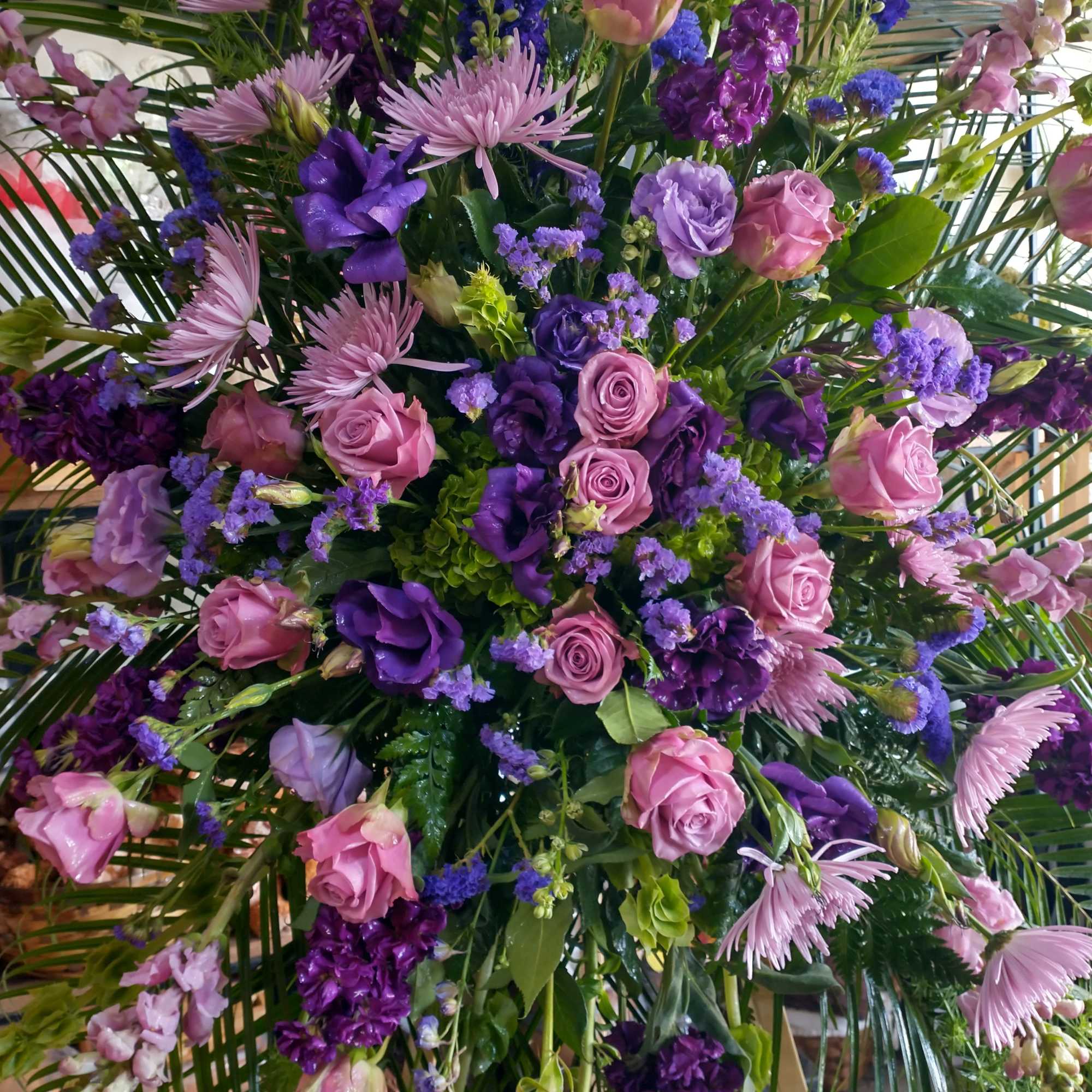 Large bouquet of pink and purple flowers with palm fronds