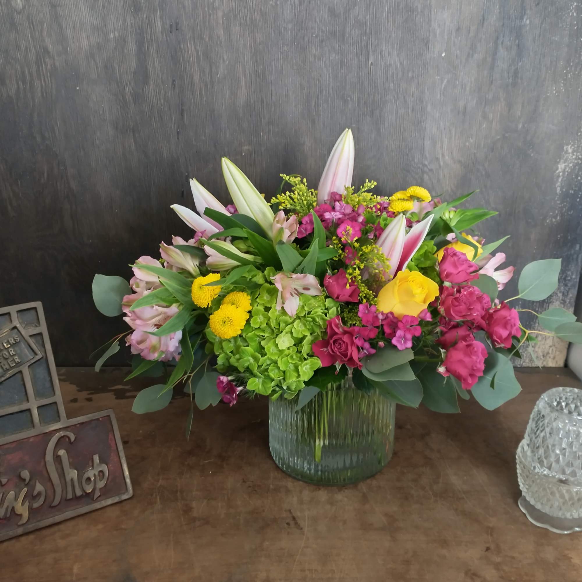 Mixed bouquet in a ribbed glass vase with pink, yellow, and white flowers