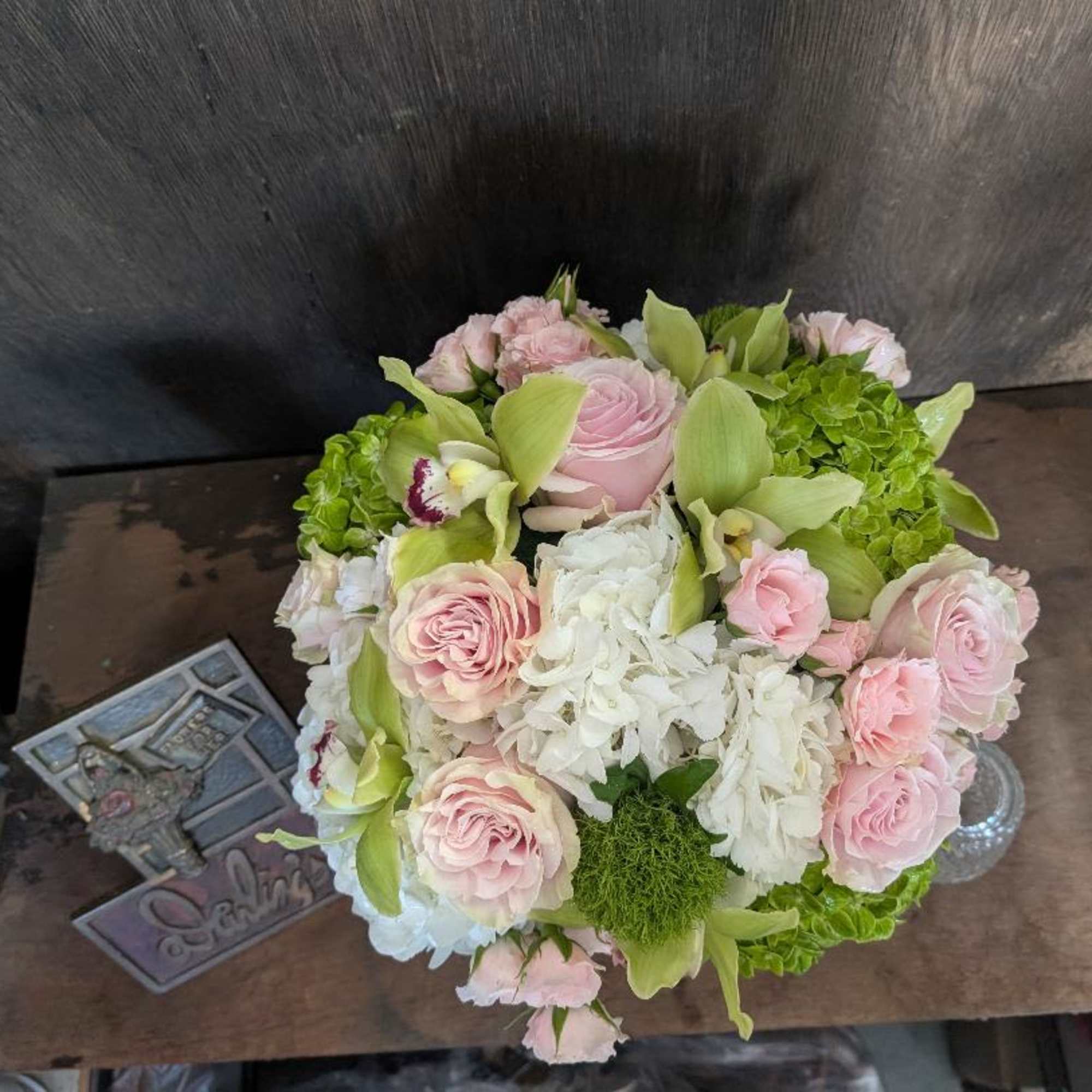Round bouquet of pale pink roses, white flowers, and green orchids