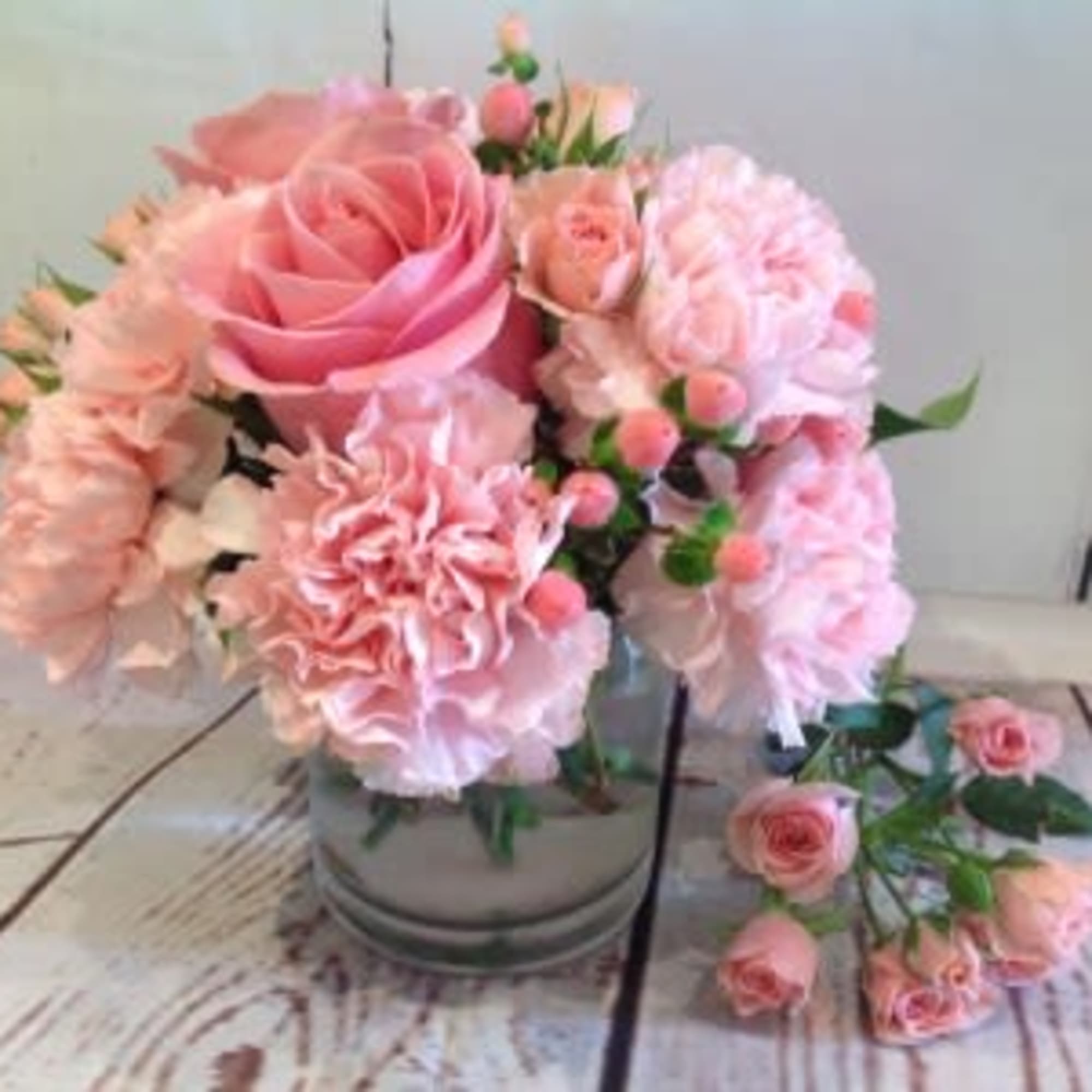 Compact pink rose and carnation arrangement in a clear glass vase