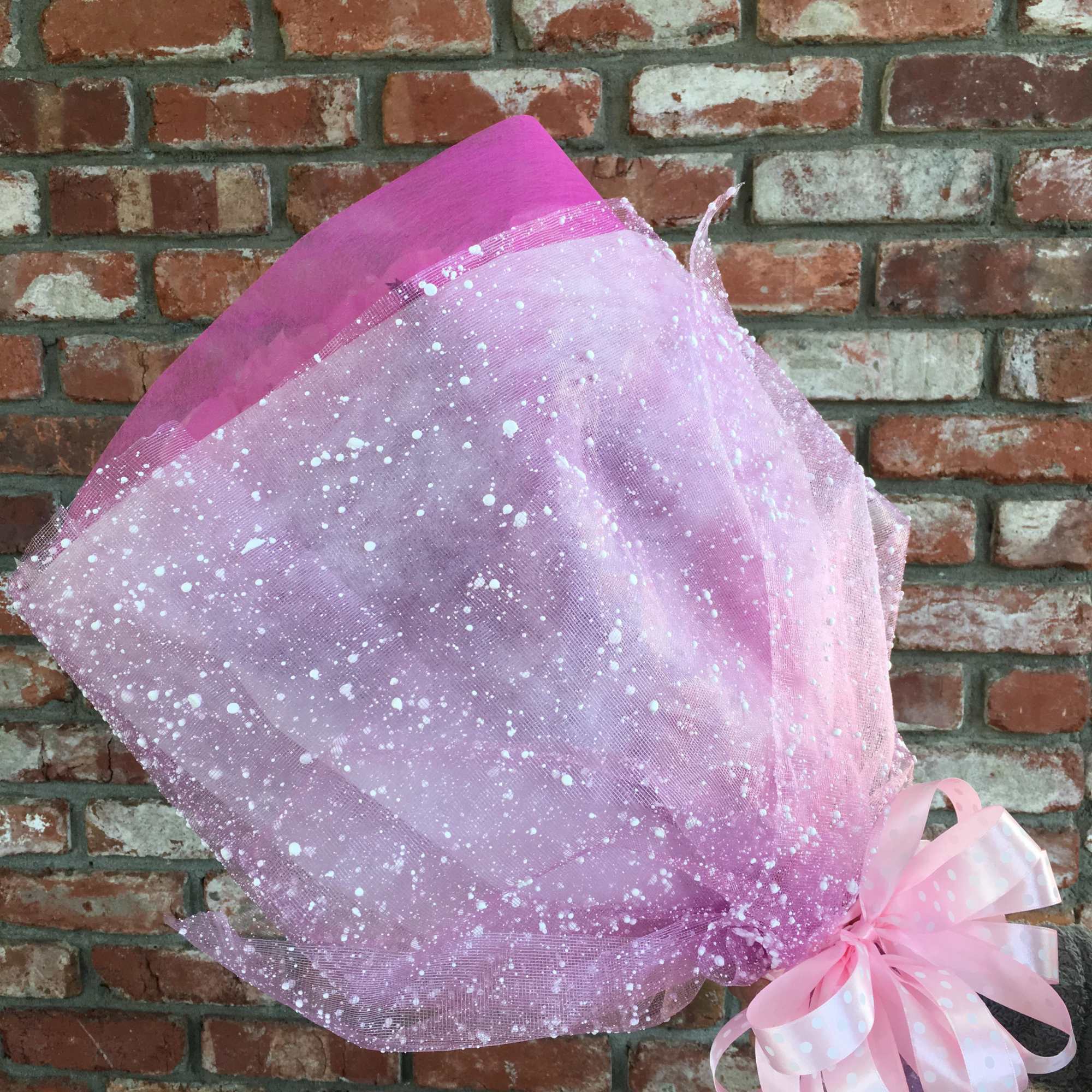 Pink mesh-wrapped bouquet with a ribbon bow