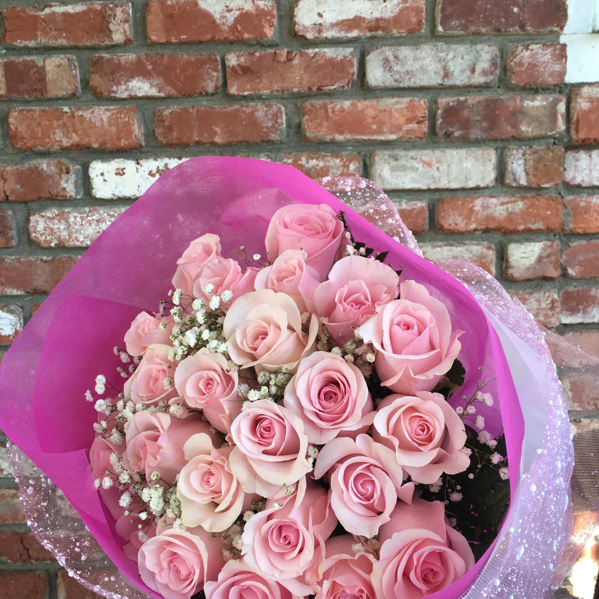 Bouquet of pale pink roses wrapped in bright pink paper