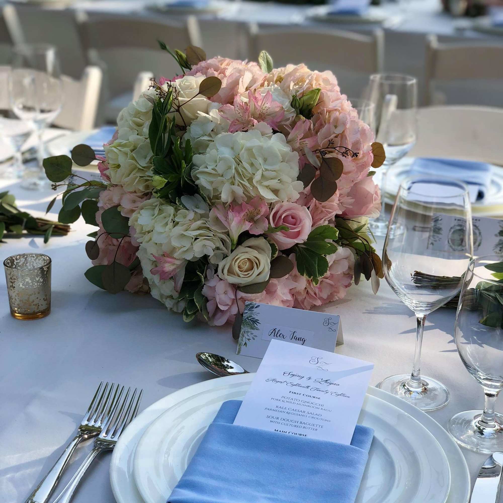 Pink and white floral centerpiece on a set dining table