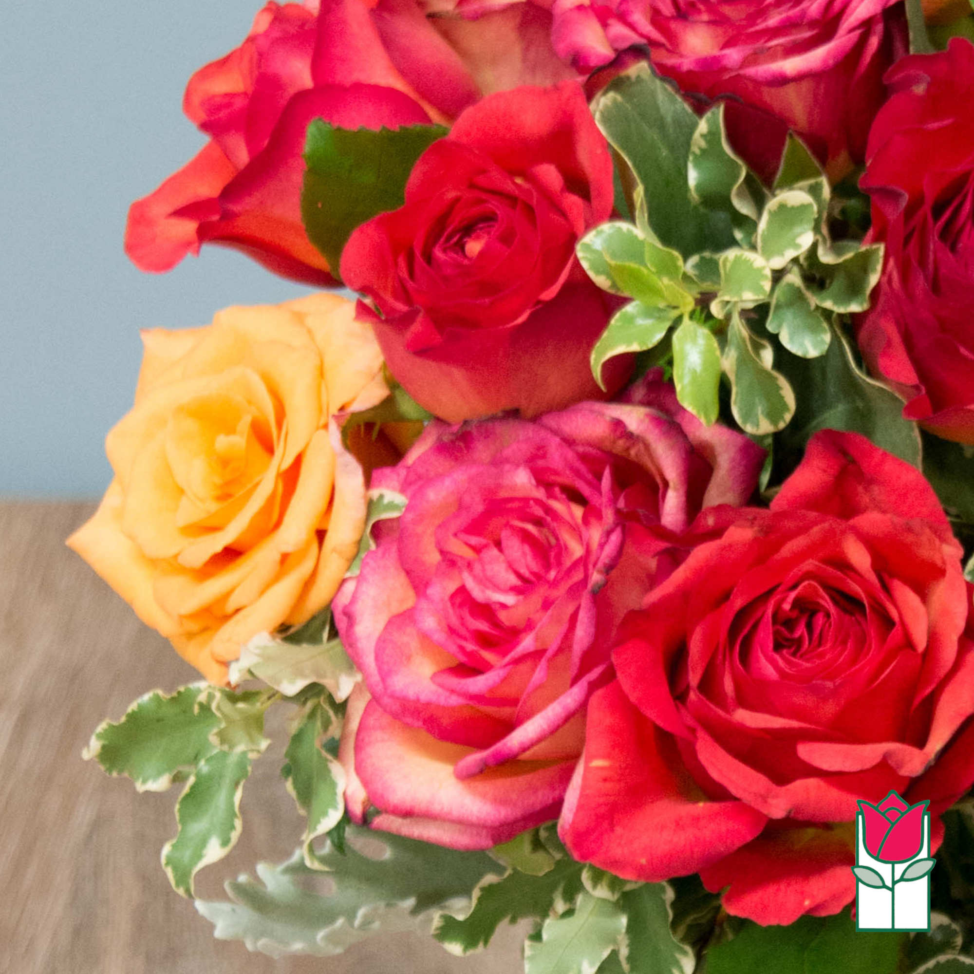 Bouquet of red, pink, and yellow roses with variegated greenery