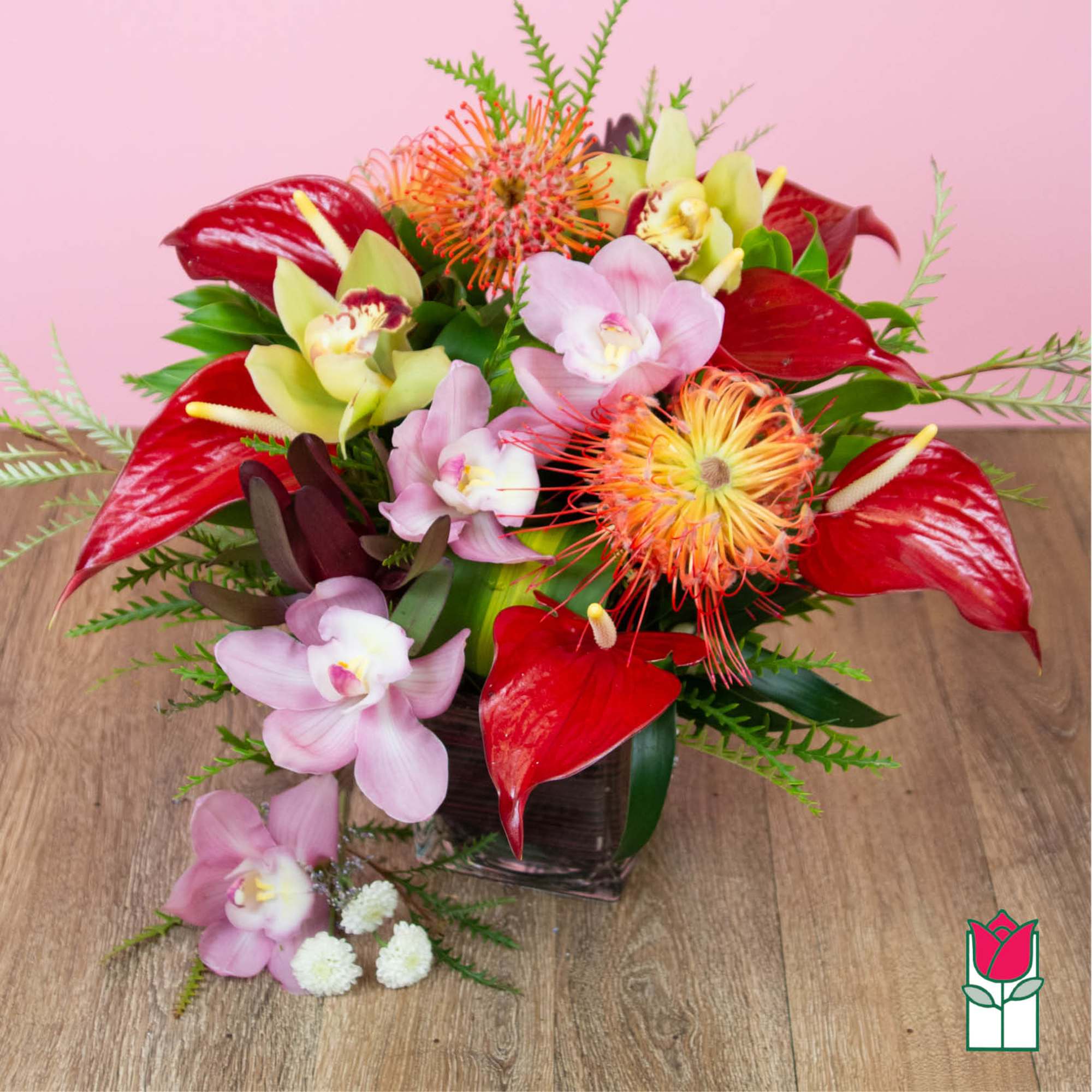 Tropical flower arrangement with red anthuriums and pink orchids in a glass vase