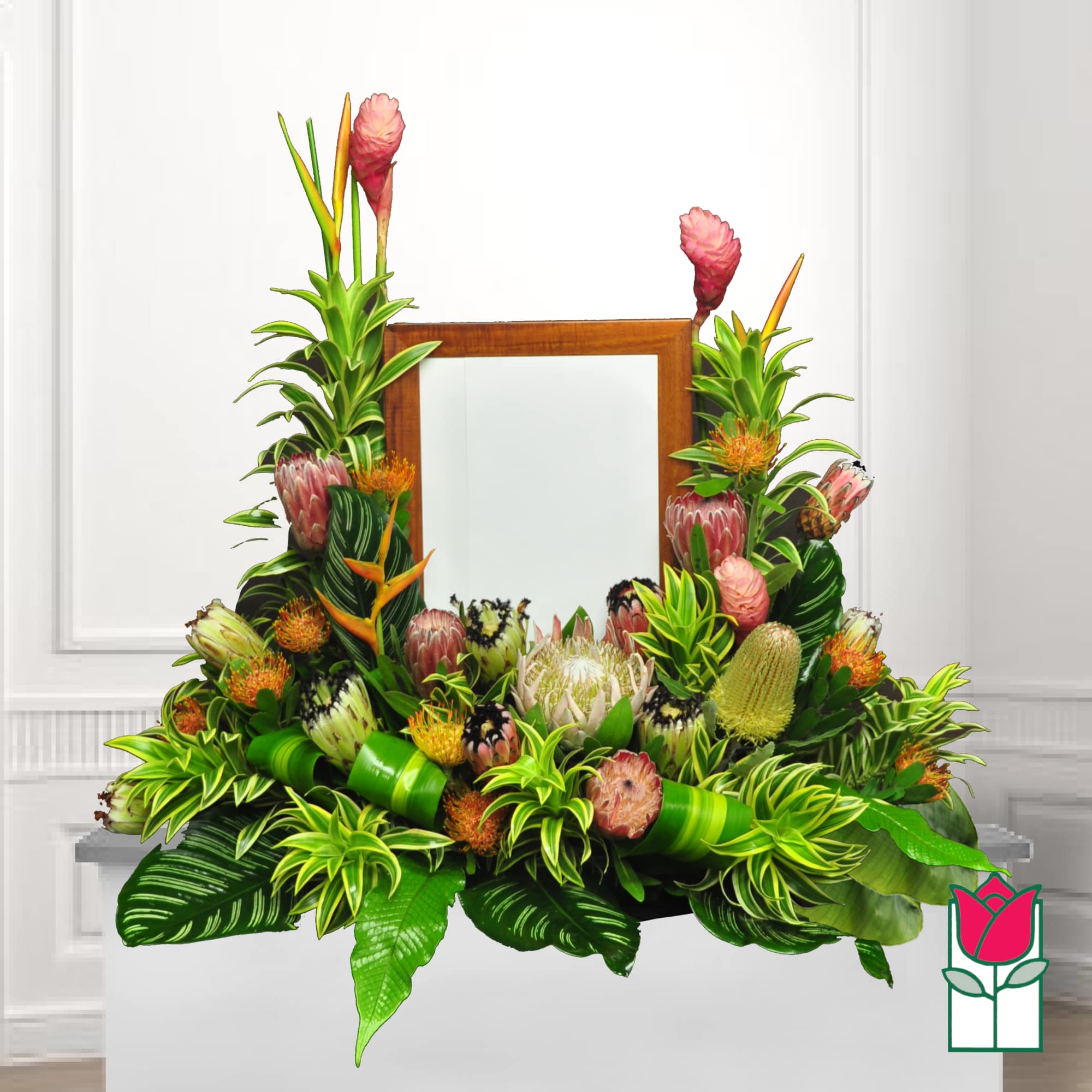 Tropical floral arrangement with protea and pink blooms around a wooden mirror frame
